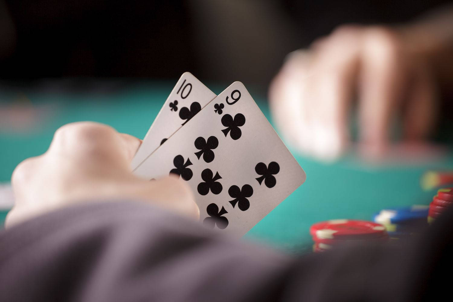 Playing Cards 桌布 壁紙 — 特寫鏡頭，雙手在綠色賭桌上拿著梅花十和九，背景有模糊的籌碼和另一隻手。