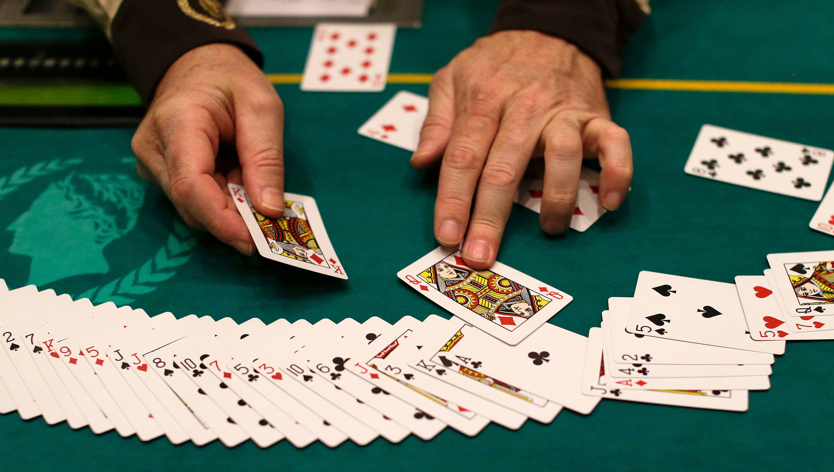 Playing Cards 桌布 壁紙 — 特寫鏡頭：雙手在綠色賭桌上發牌，桌上散落著籌碼，並可見同花順。
