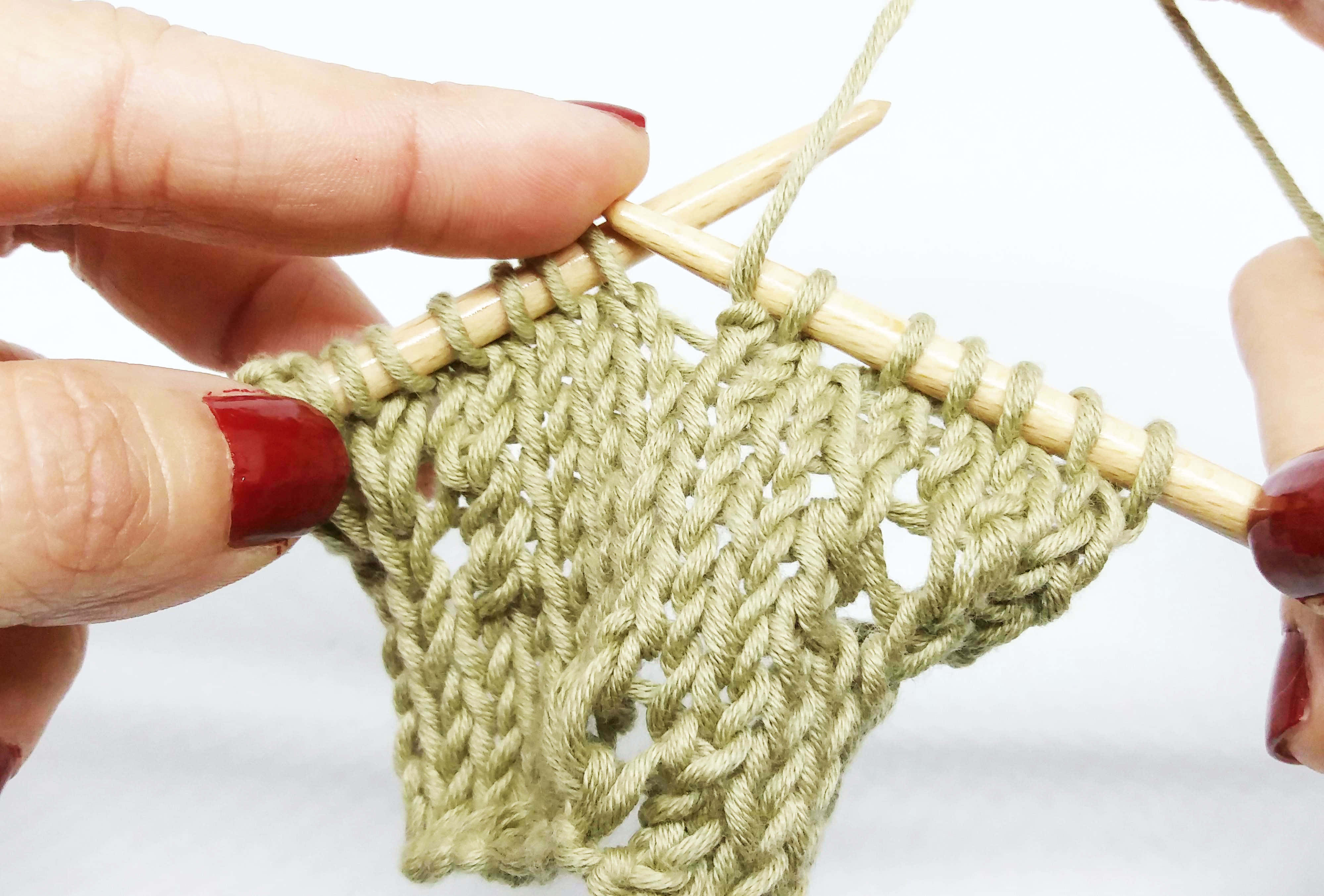 Butterfly Stitch 桌布 壁紙 — 特寫鏡頭，雙手塗有紅色指甲油，用木針在白色背景上編織綠色毛線樣品。