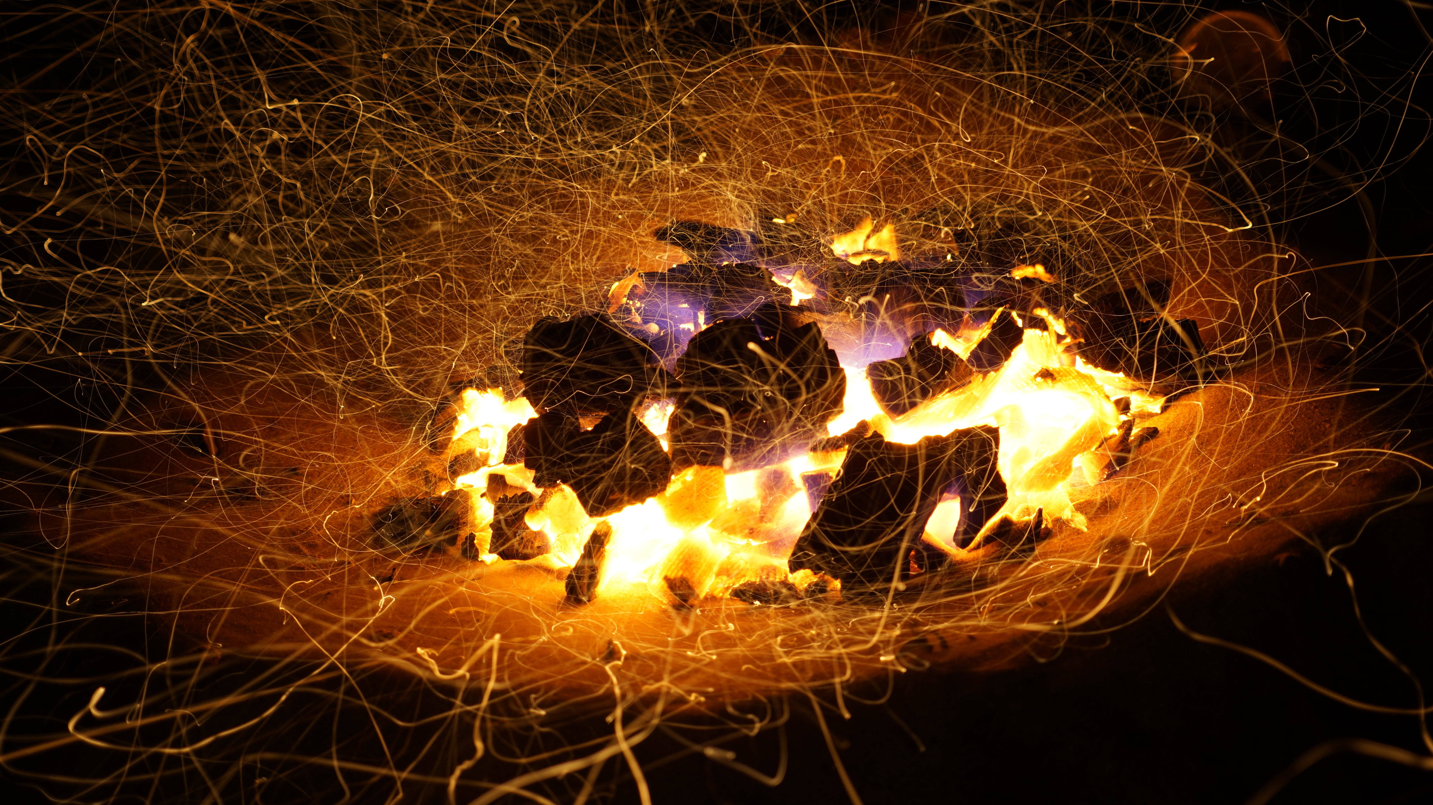 Temperature 桌布 壁紙 — 特寫鏡頭，顯示在黑暗背景下從火中飛出的熾熱餘燼和火花。