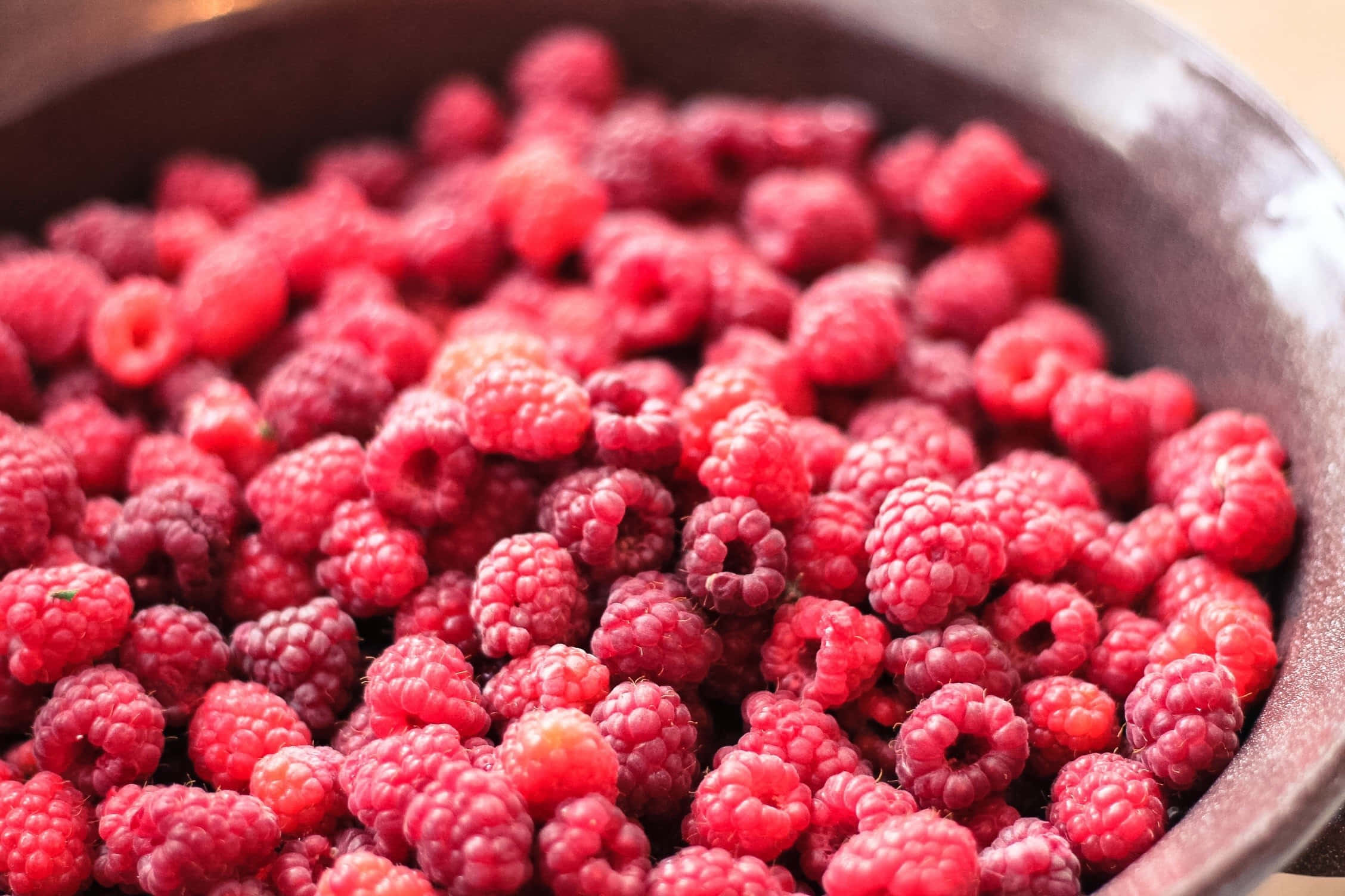 Raspberry 桌布 壁紙 — 特寫鏡頭：飽滿多汁的覆盆子在深色鄉村風碗中滿溢，柔和自然光線照射。