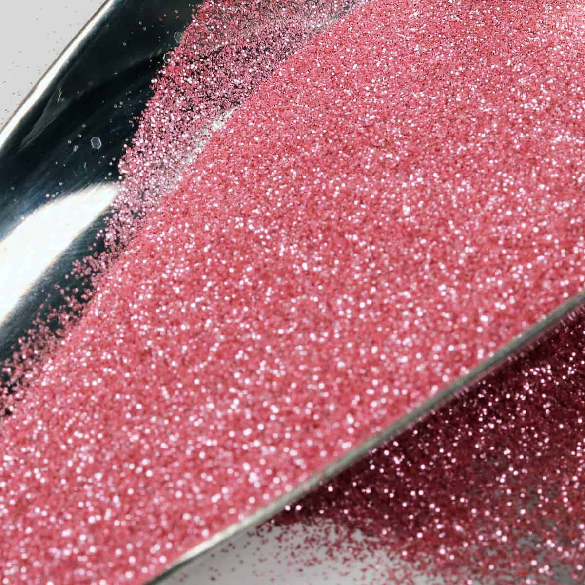 Pink Sparkles 桌布 壁紙 — 特寫鏡頭：鮮豔粉紅閃粉從金屬勺中灑落在中性背景上。