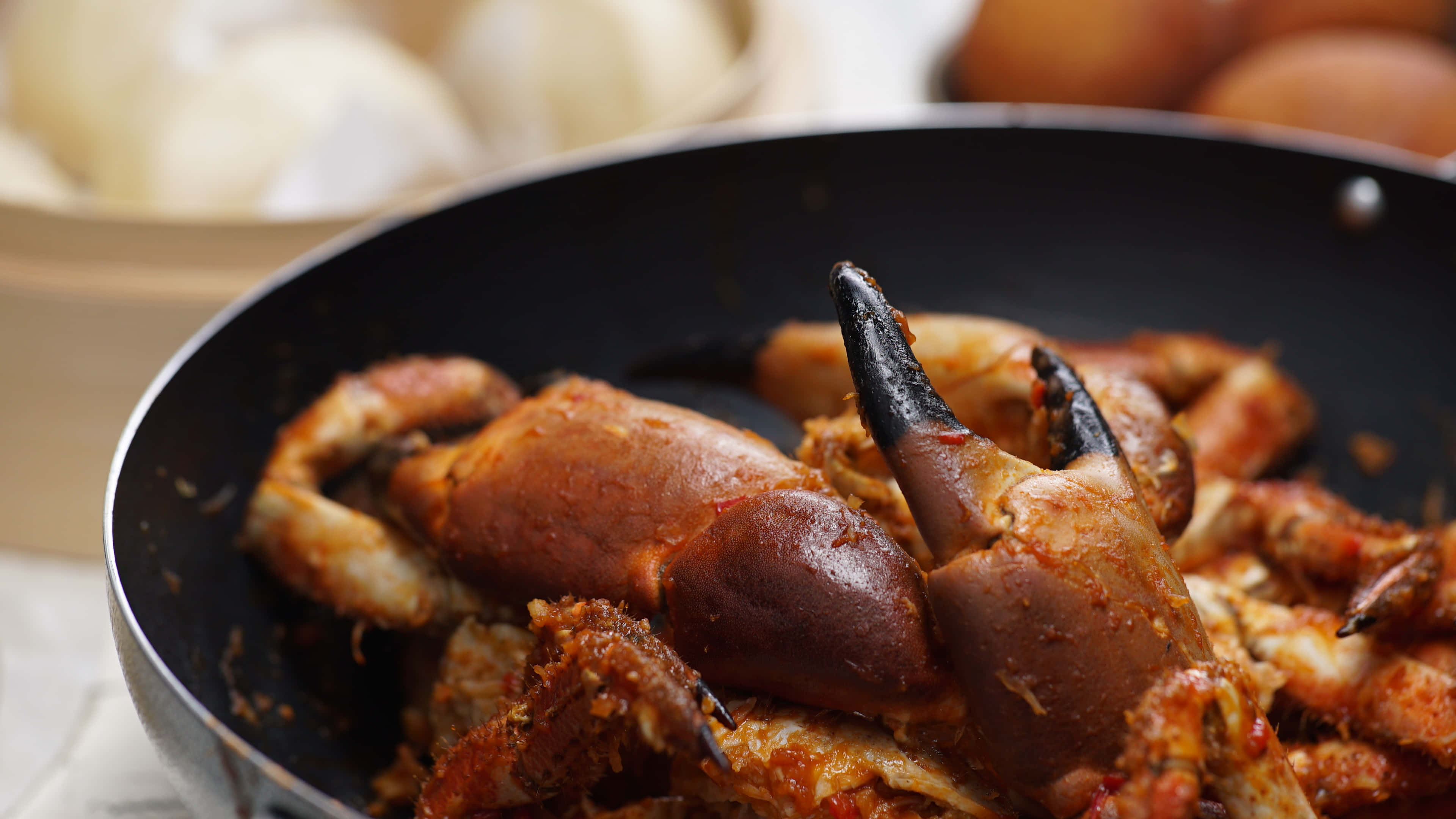 Crab 桌布 壁紙 — 特寫鏡頭：黑色煎鍋中滋滋作響的辣蟹鉗，背景是模糊的餃子和雞蛋。