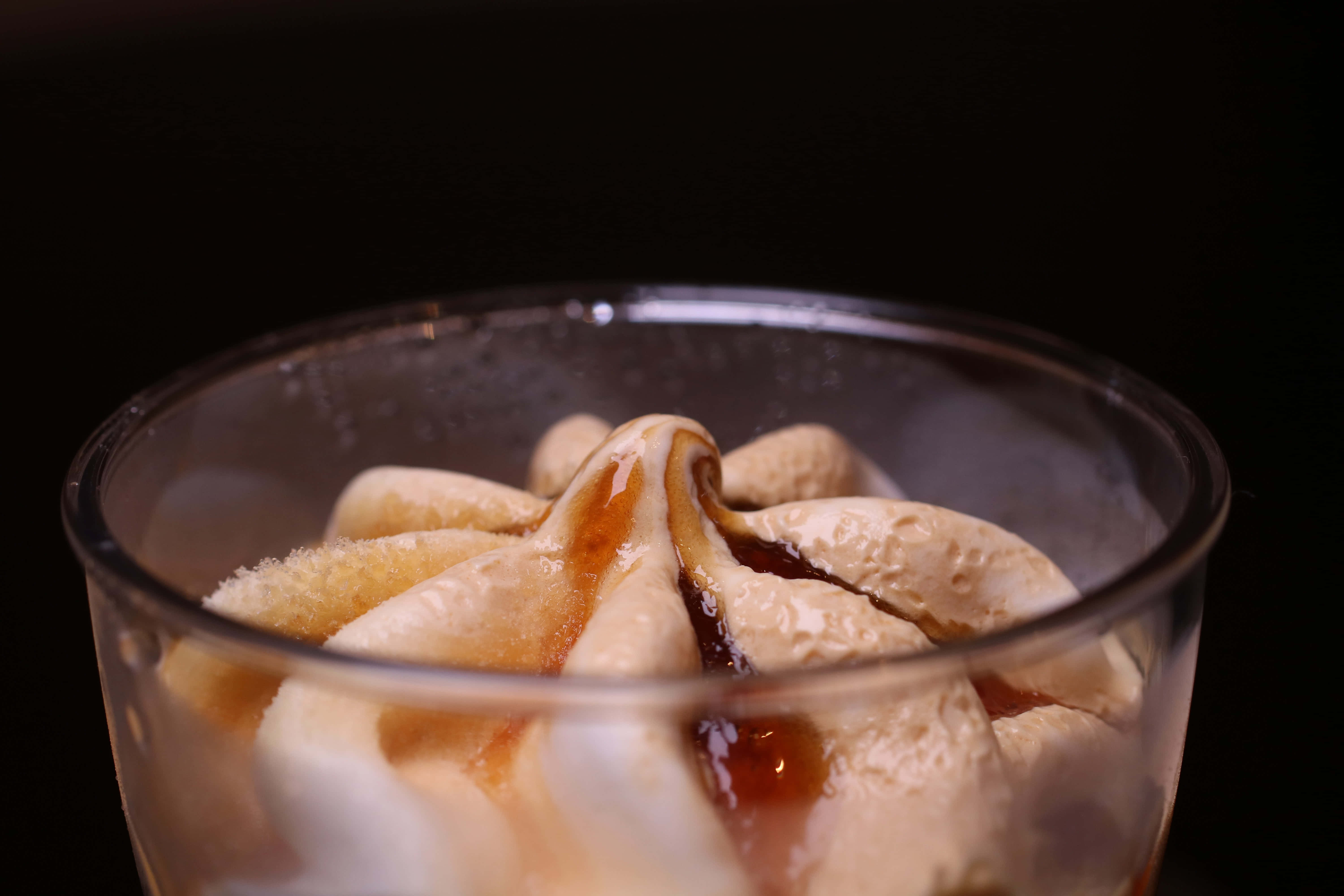 Caramel 桌布 壁紙 — 特寫鏡頭：黑色背景前，透明玻璃碗中旋有焦糖醬的奶油香草冰淇淋。