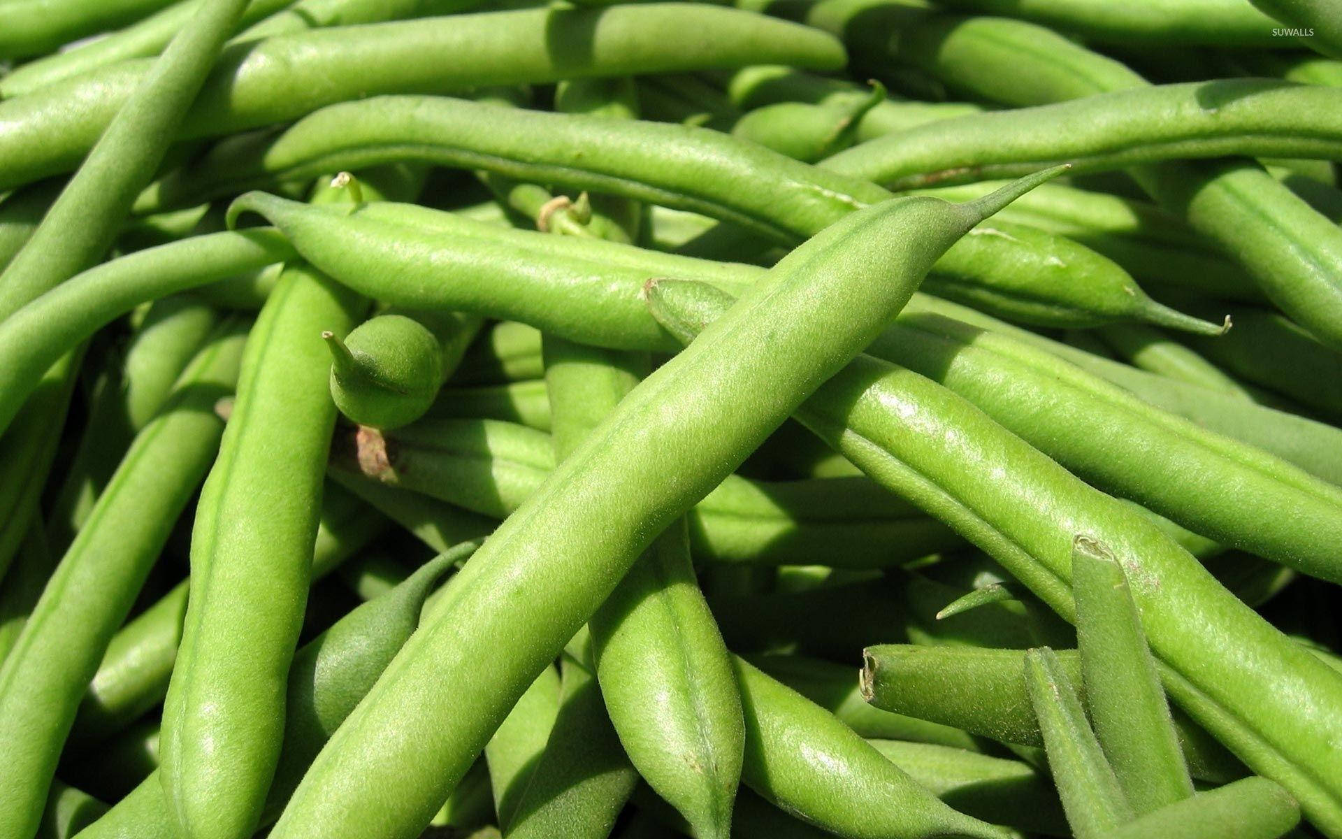 vegan 桌布 壁紙 — 特寫鏡頭下，鮮綠的豆子在明亮陽光下堆疊在一起，展現出自然紋理和光澤表面。