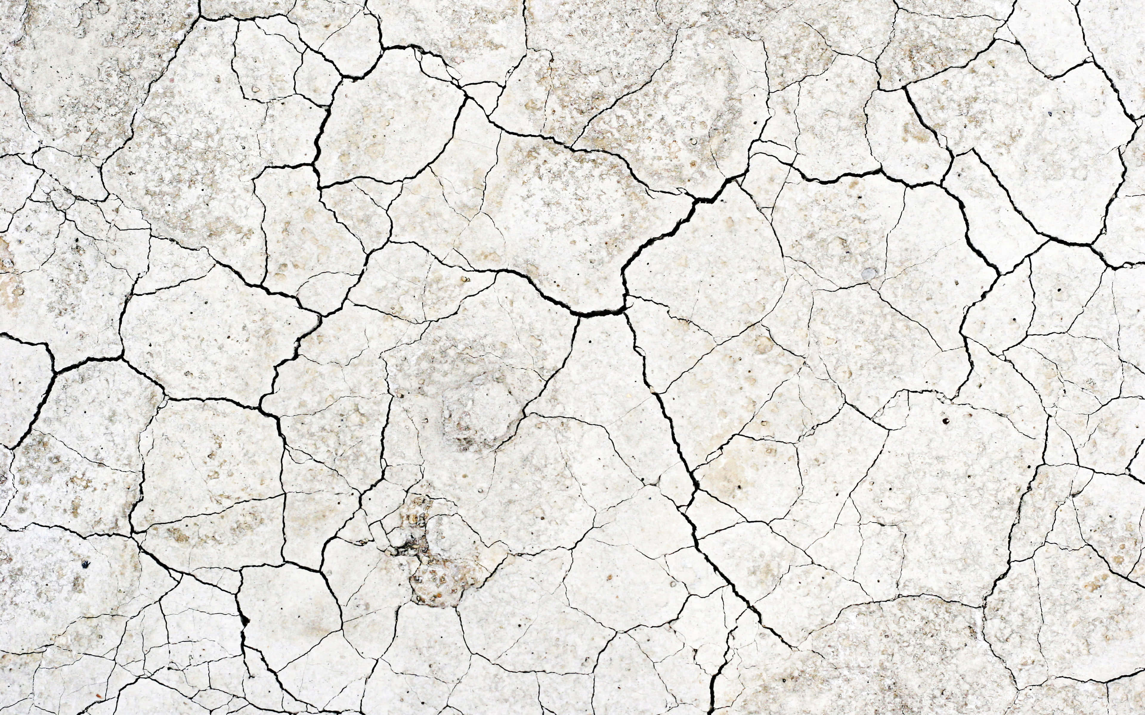 Cracks Texture 桌布 壁紙 — 特寫鏡頭下的乾裂土地，深色裂縫在明亮光線下形成破碎的馬賽克圖案。