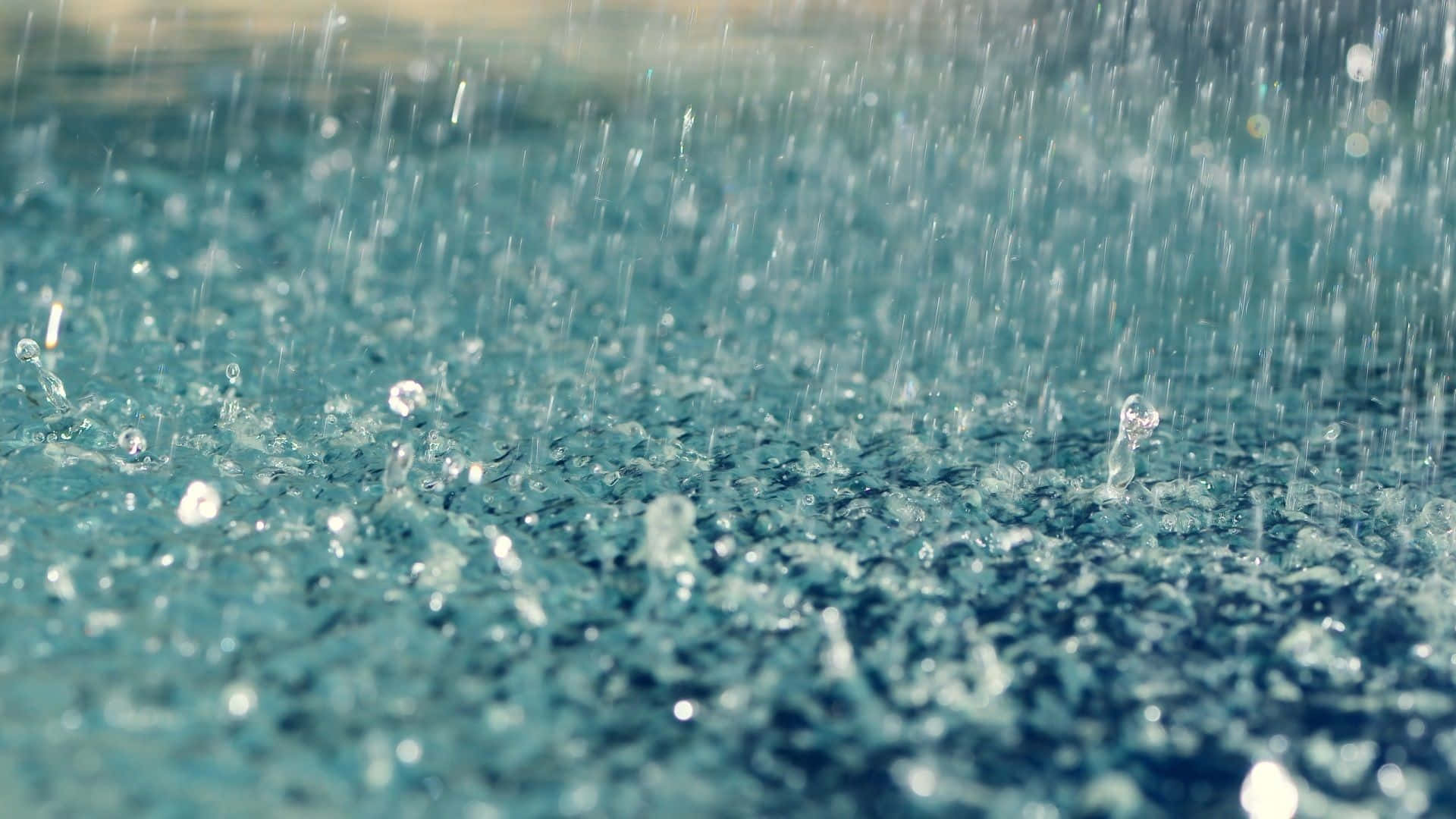 Raining 桌布 壁紙 — 特寫鏡頭中，雨滴在帶有紋理的青綠色水面上飛濺並泛起漣漪。