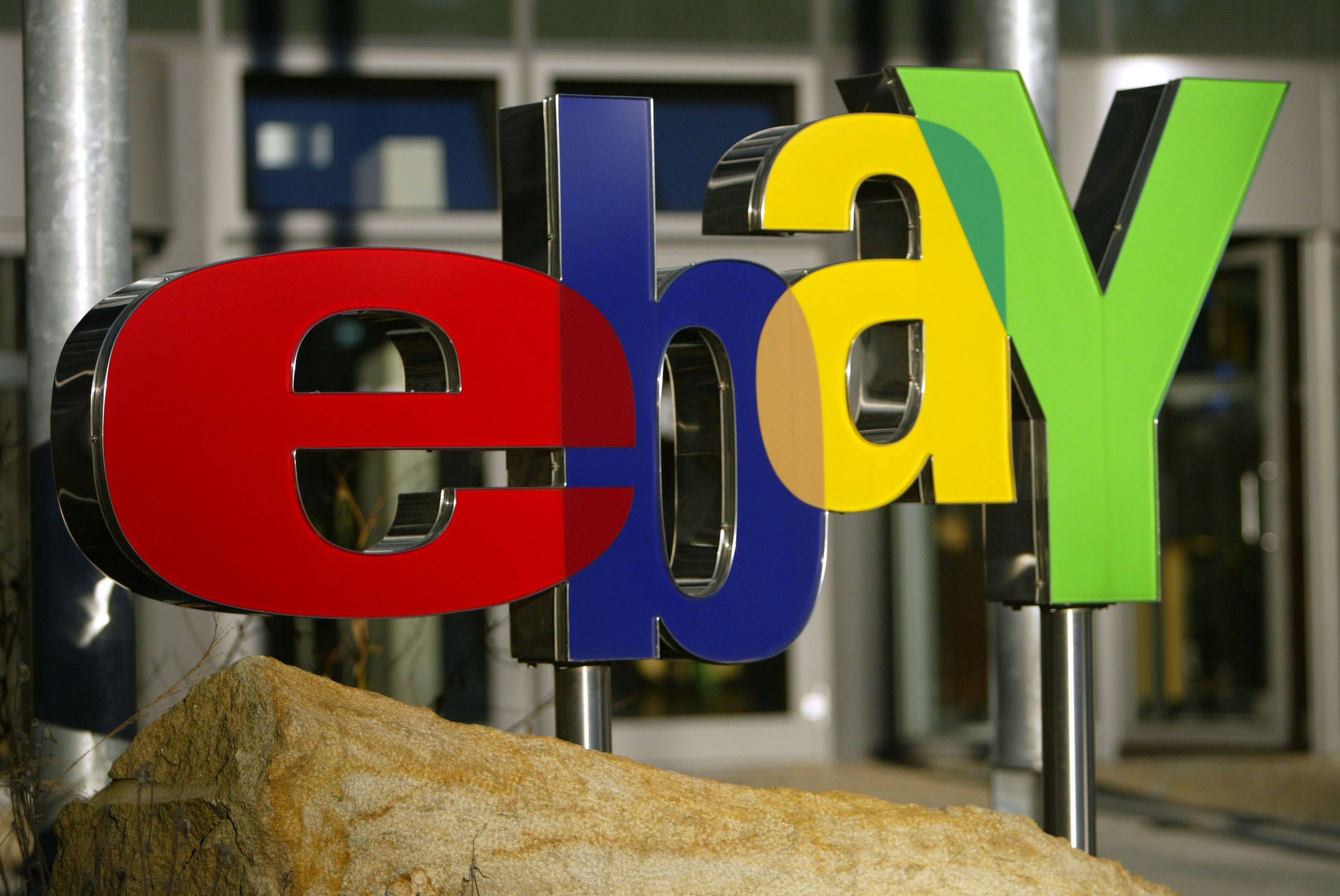 eBay 桌布 壁紙 — 特寫鏡頭顯示色彩繽紛的eBay標誌字母安裝在柱子上，前景有一塊大石頭。