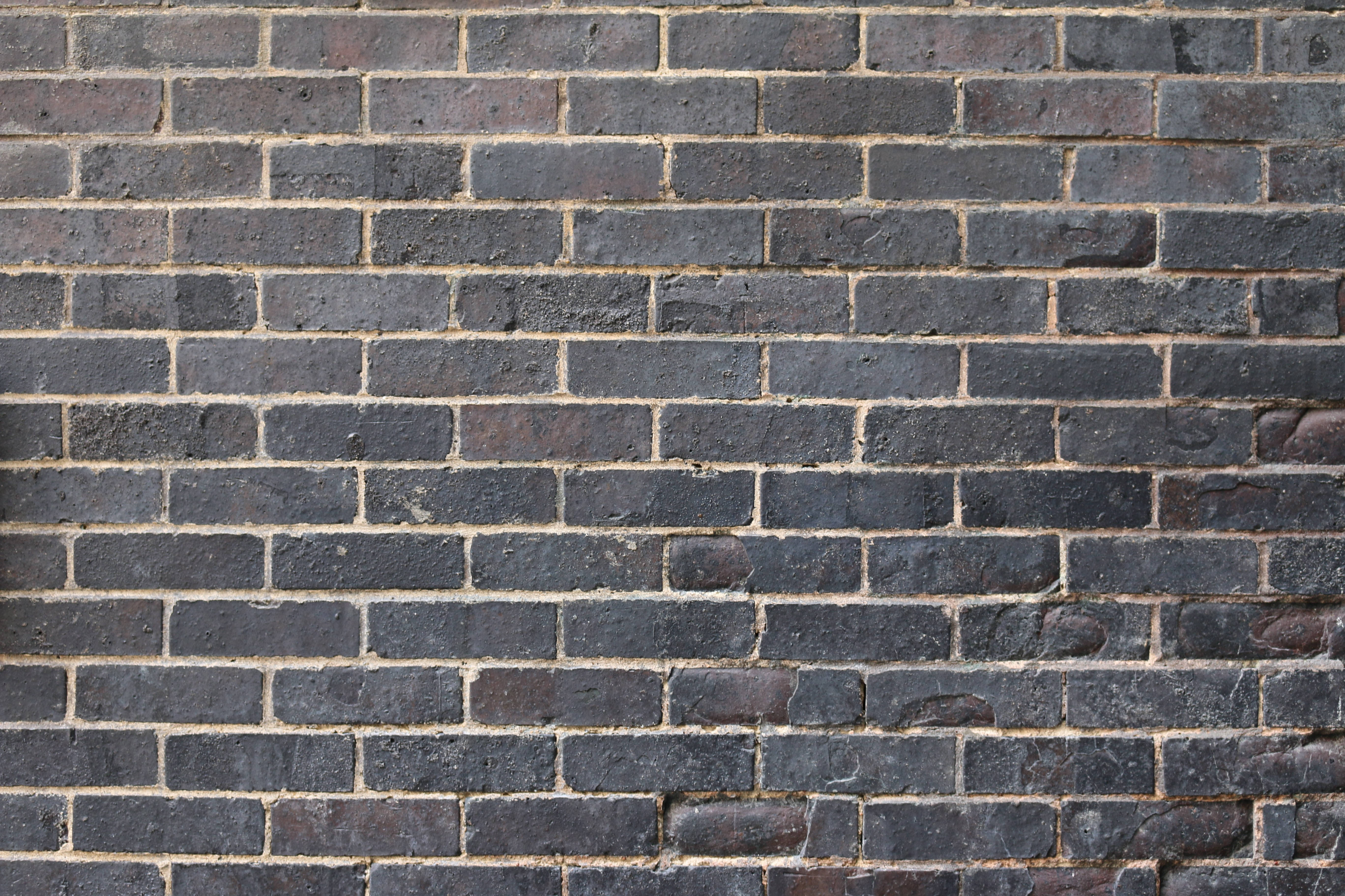 Brick 桌布 壁紙 — 特寫風化深灰色磚塊與淺米色砂漿形成紋理城市牆面。