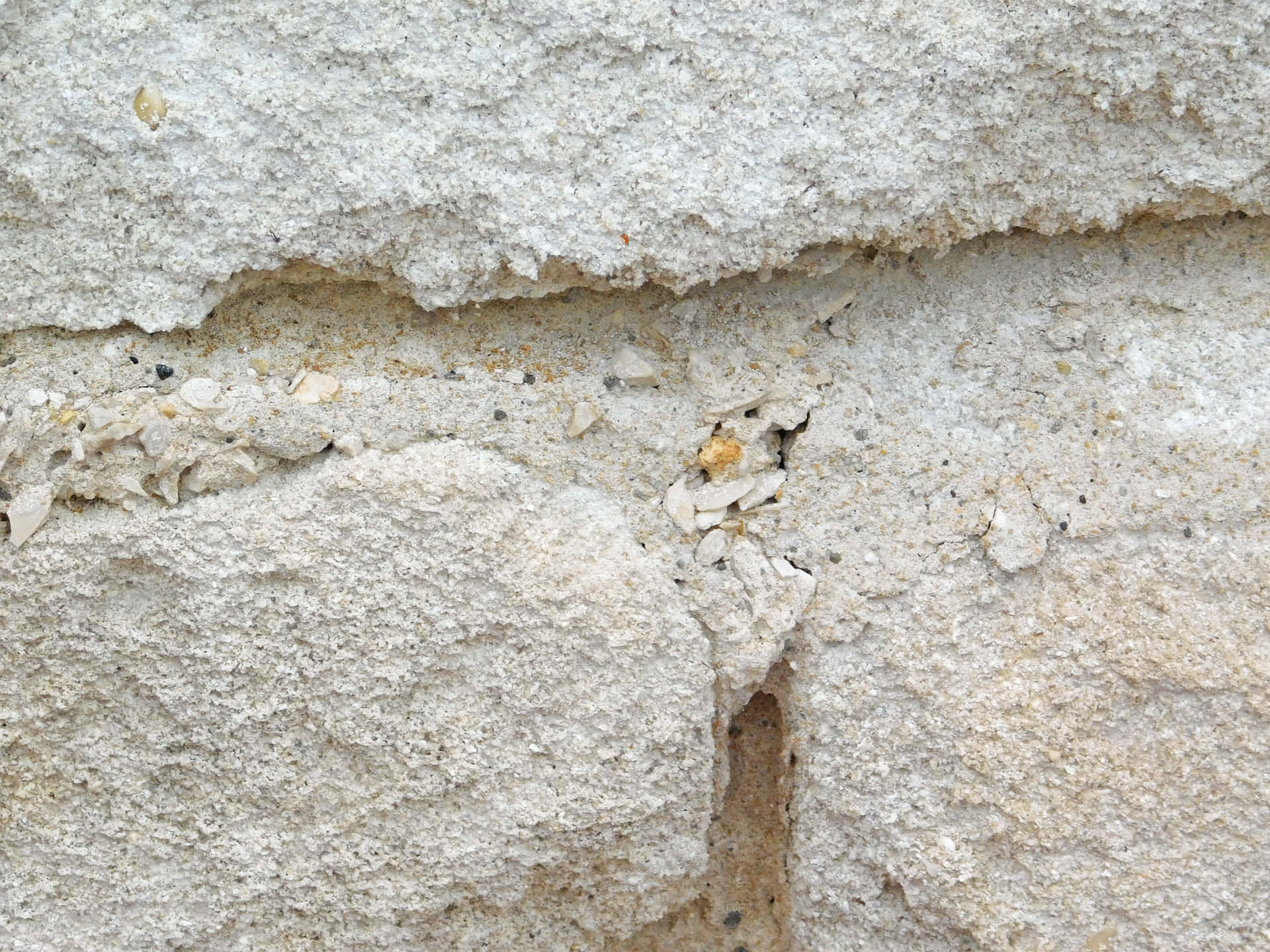Stone texture 壁紙 — 特寫風化淺灰色混凝土牆，可見裂縫和嵌入的小石頭。