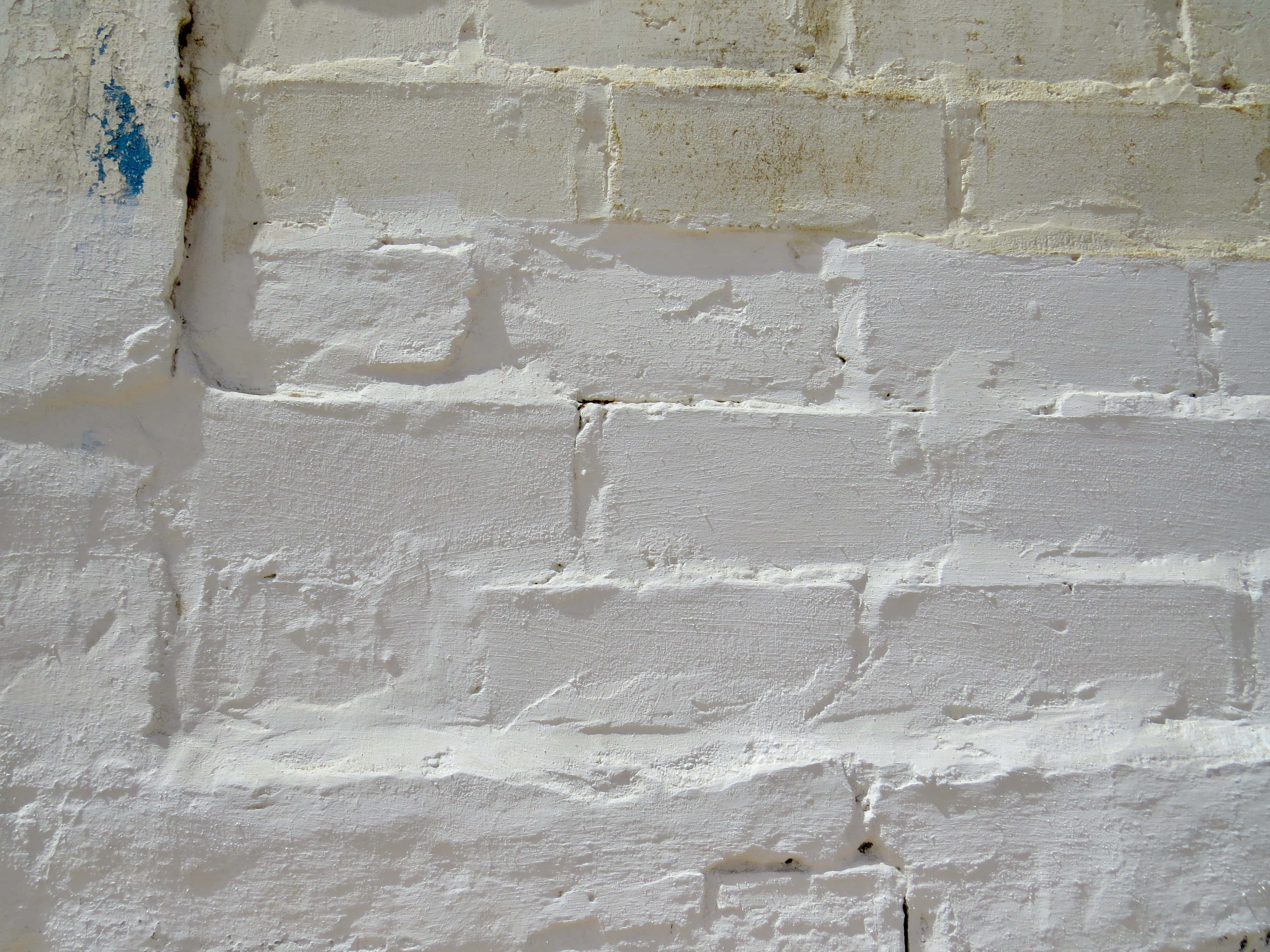 White Brick Wall 桌布 壁紙 — 特寫風化白色油漆磚牆，帶有紋理砂漿和微弱的藍色油漆斑點。