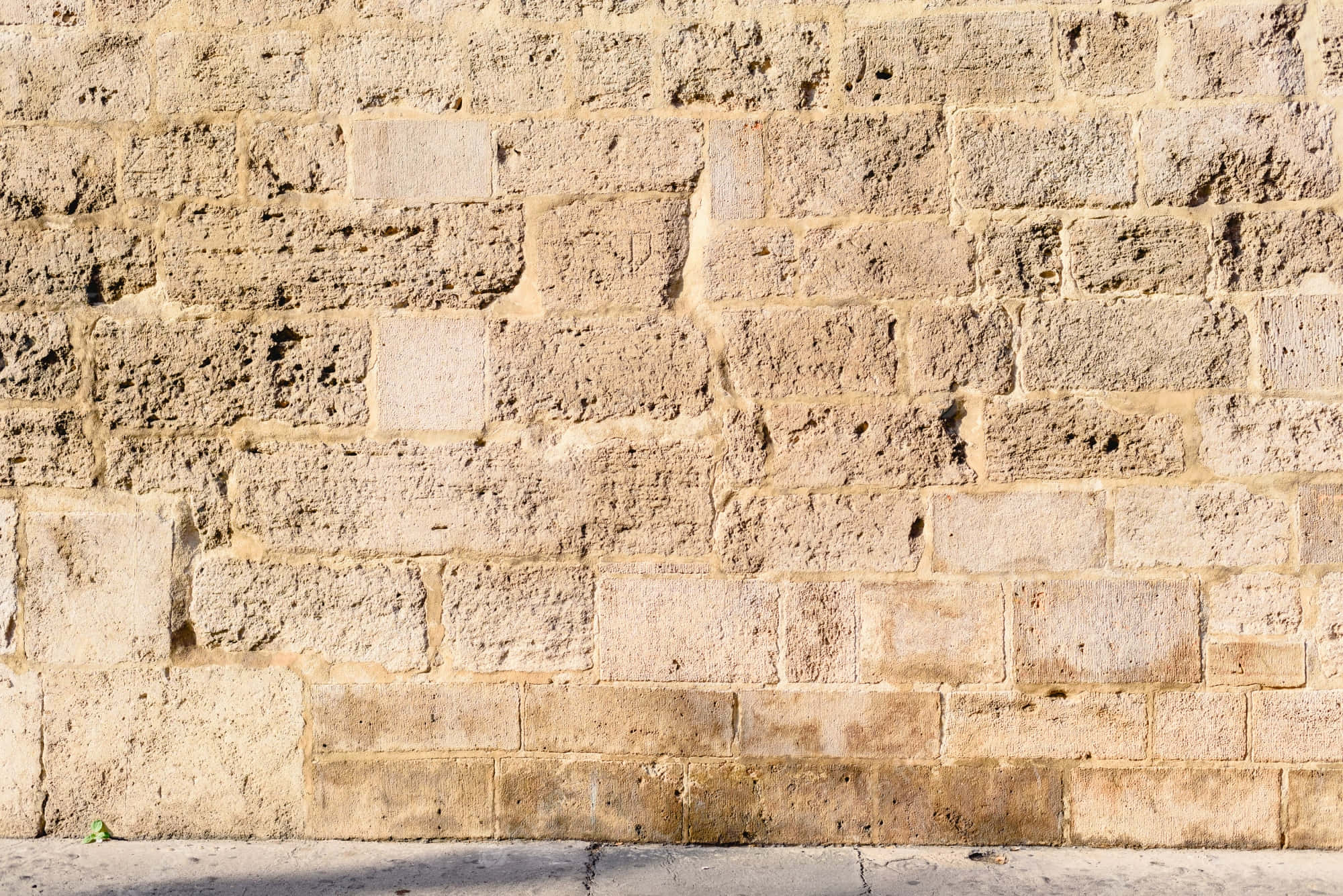 Stone Wall 桌布 壁紙 — 特寫風化的米色石磚在明亮日光下形成有紋理的古老牆壁。