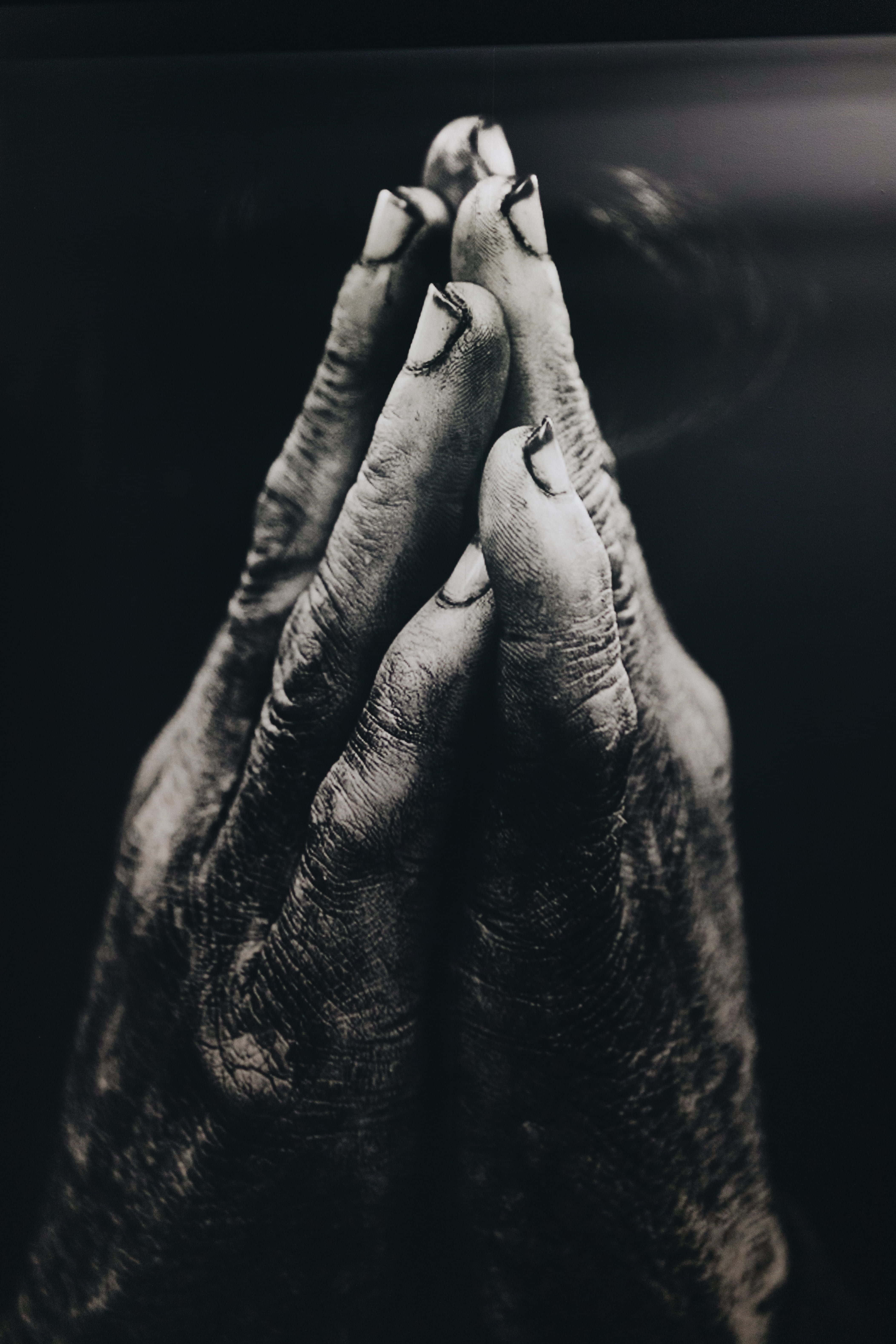 Praying 桌布 壁紙 — 特寫黑白照片，顯示一雙飽經風霜的手在黑暗背景中合十祈禱。
