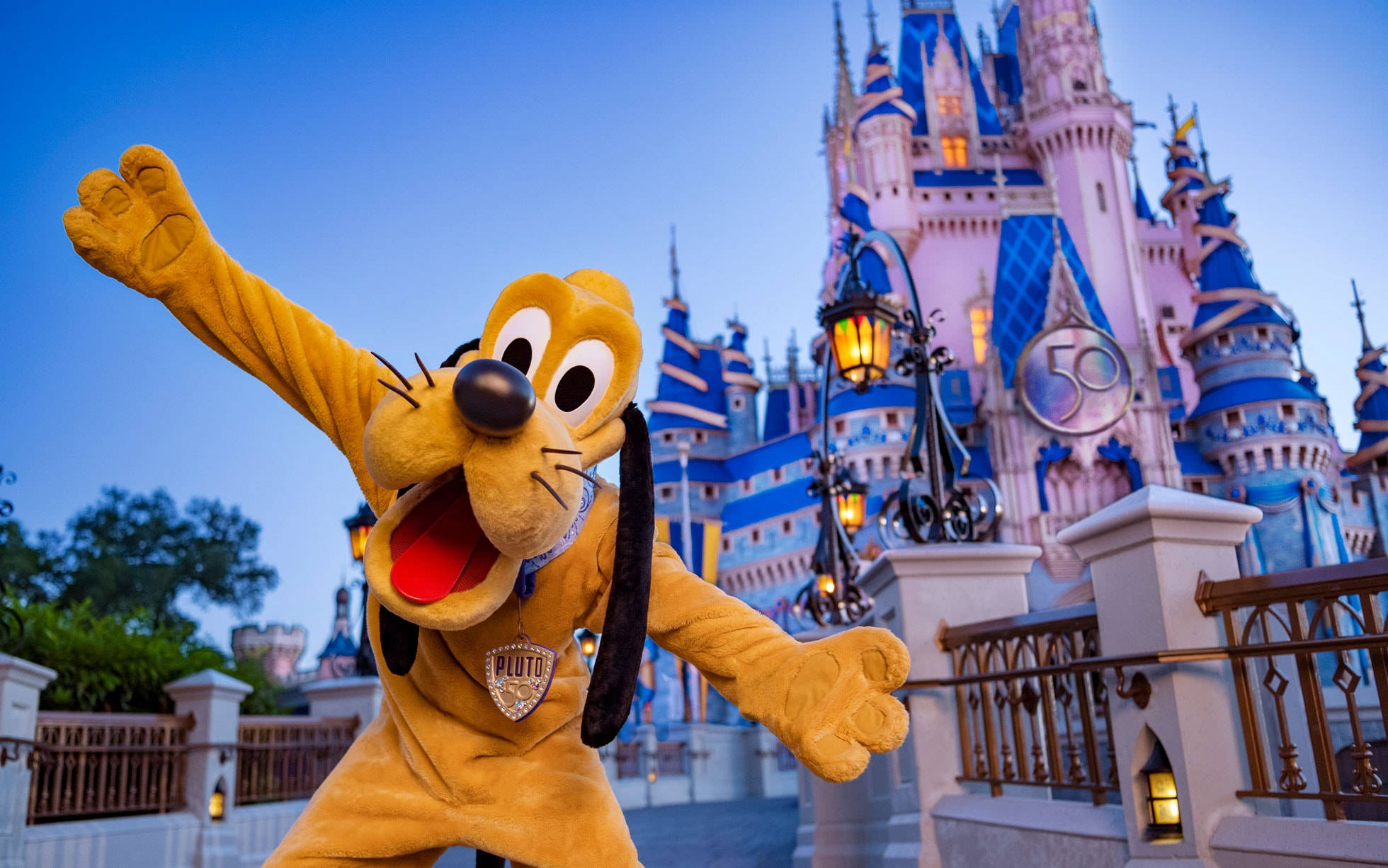 城堡動畫 桌布 壁紙 — 狗狗米奇角色布魯托在黃昏時發光的迪士尼城堡前開心揮手。