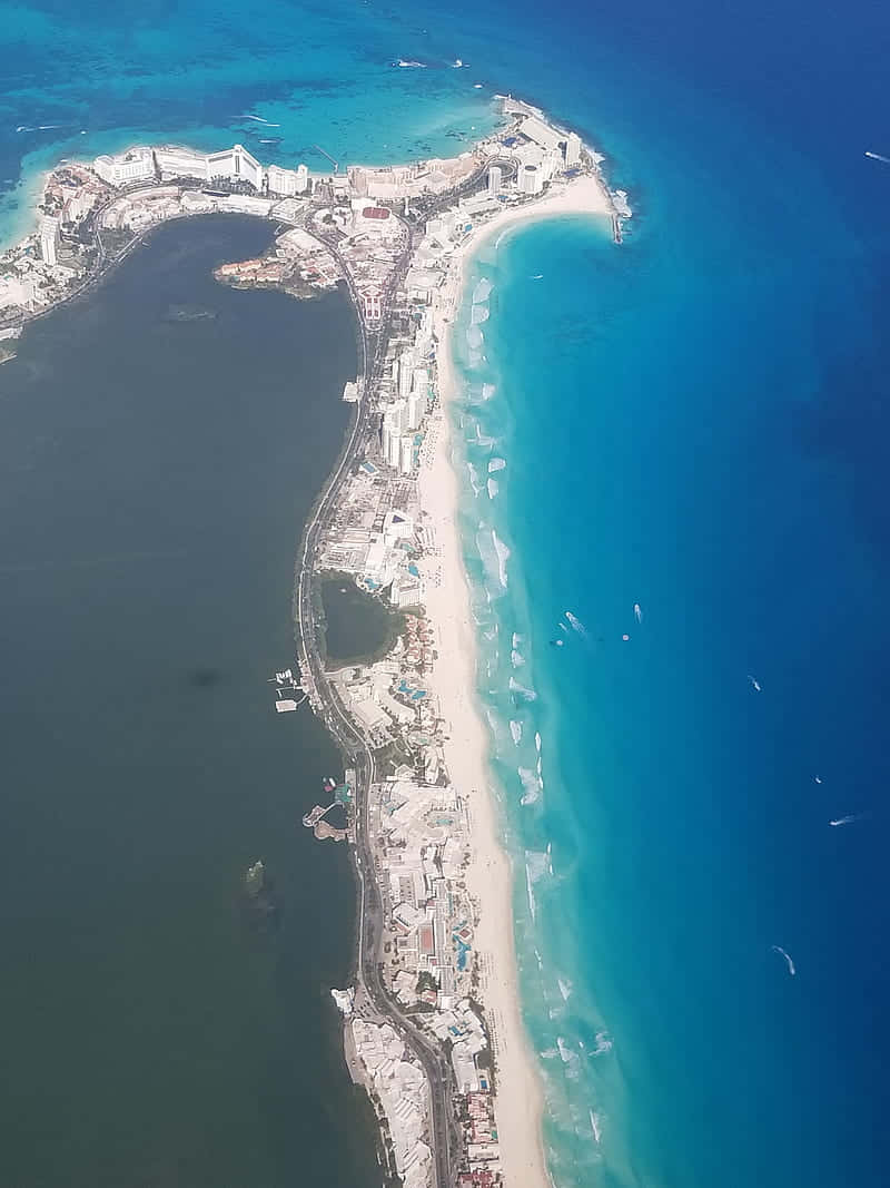 島嶼 桌布 壁紙 — 狹窄沿海半島的鳥瞰圖，擁有白色沙灘、碧綠海水和密集的度假村建築沿著海岸線排列。