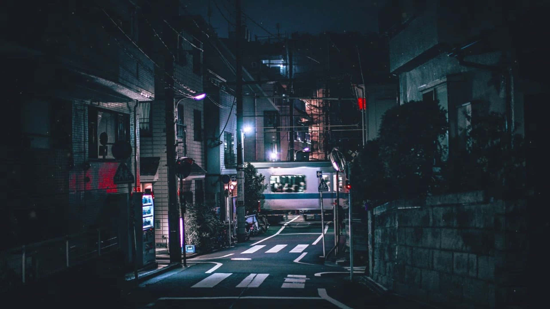 Night Street 桌布 壁紙 — 狹窄的城市小巷在夜晚被霓虹燈和街燈照亮，遠處有火車經過。