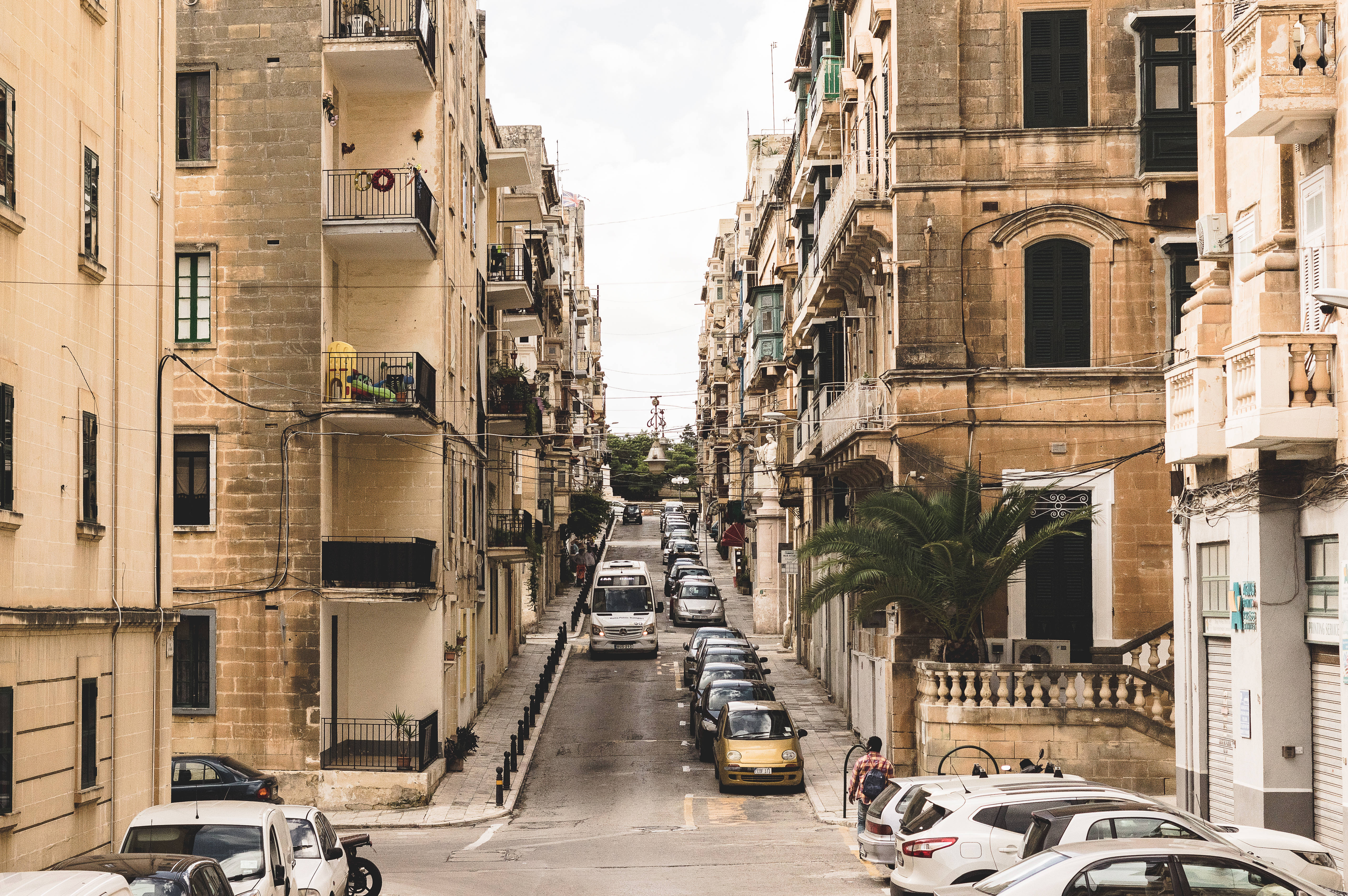 Malta 桌布 壁紙 — 狹窄街道兩旁是歷史悠久的石建築和停泊的汽車，天空多雲。