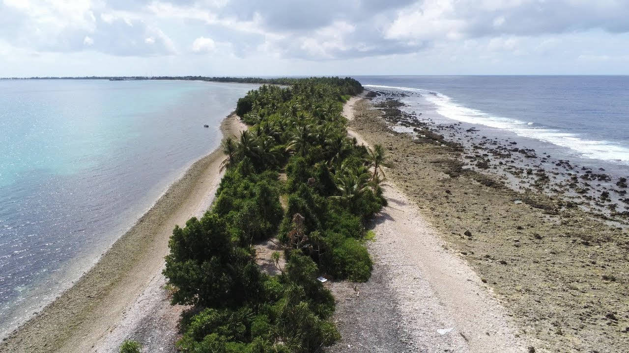 海洋 桌布 壁紙 — 狹長熱帶島嶼的鳥瞰圖，島上棕櫚樹茂盛，兩側是碧綠和深藍色的海水。