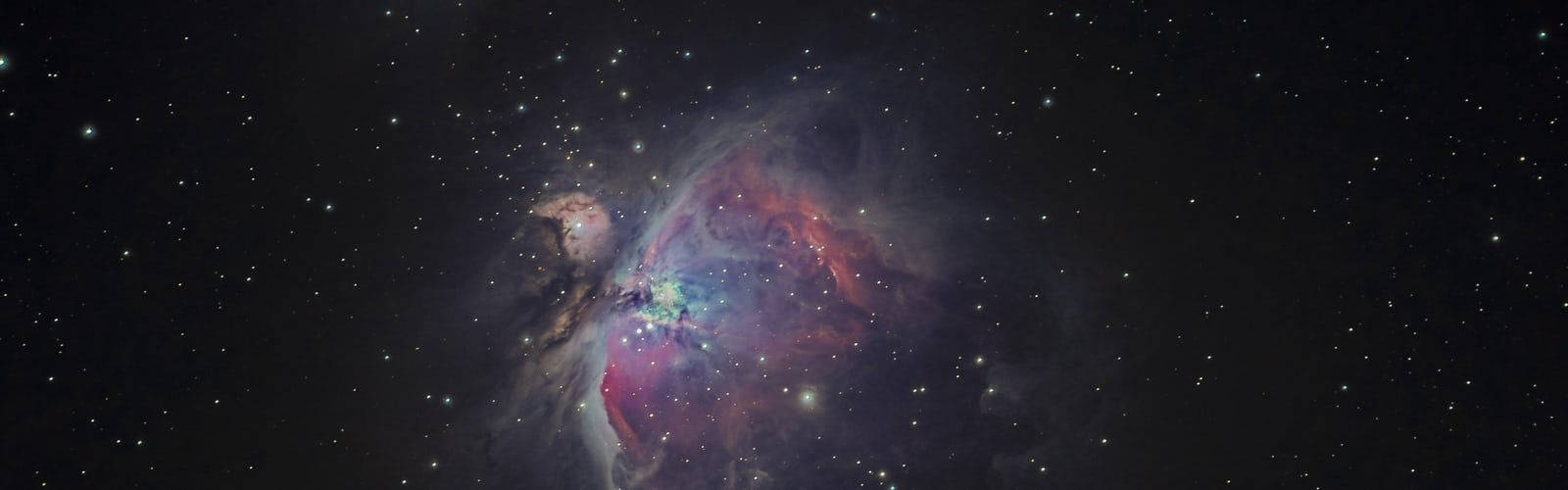 Star Space 桌布 壁紙 — 獵戶座星雲在星空背景下散發出鮮豔的紅色、紫色和藍色光芒，令人嘆為觀止。