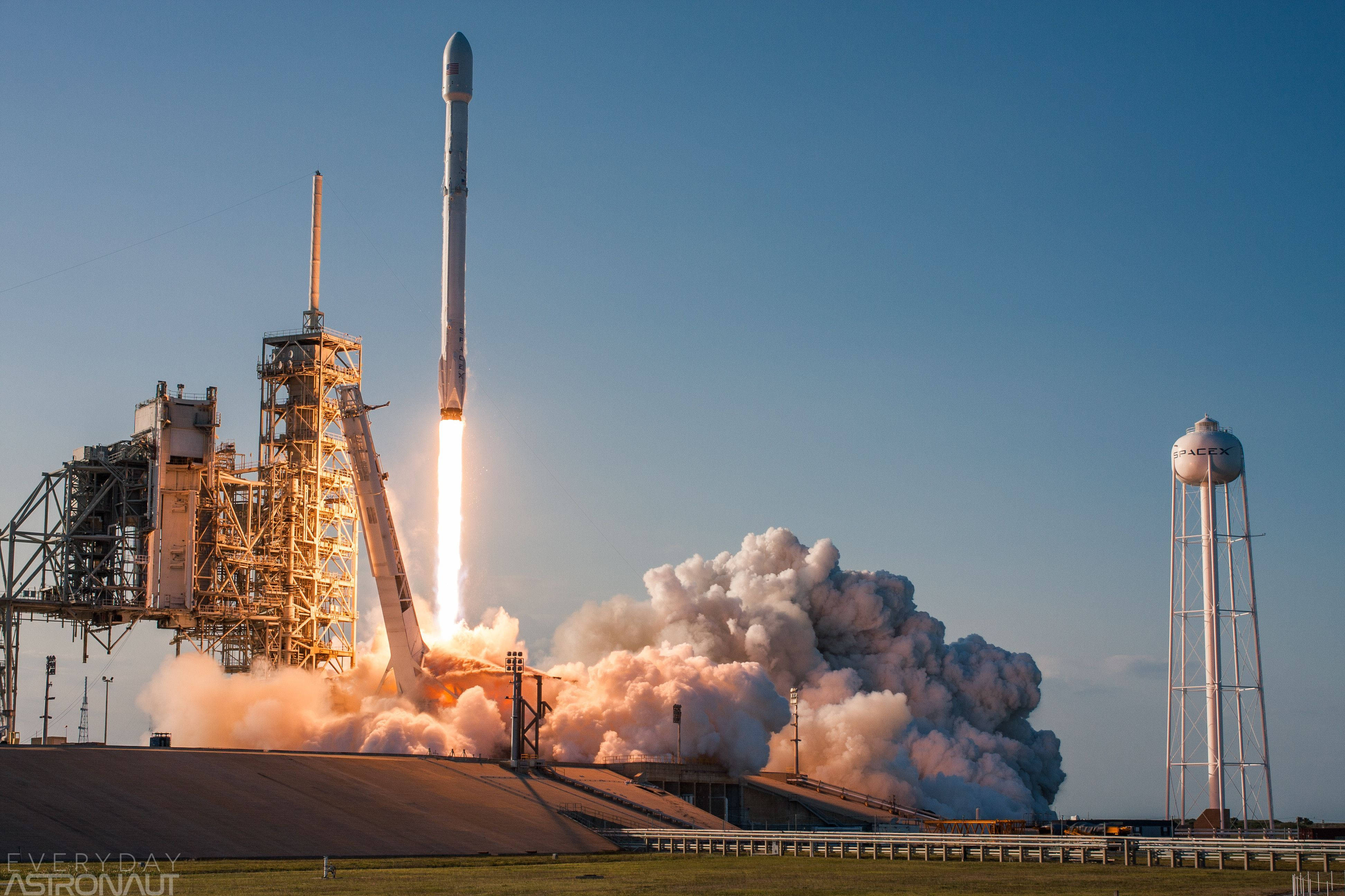 SpaceX 桌布 壁紙 — 獵鷹9號火箭在發射台點火升空，噴出熾熱的廢氣和滾滾濃煙，映襯著清澈的藍天。