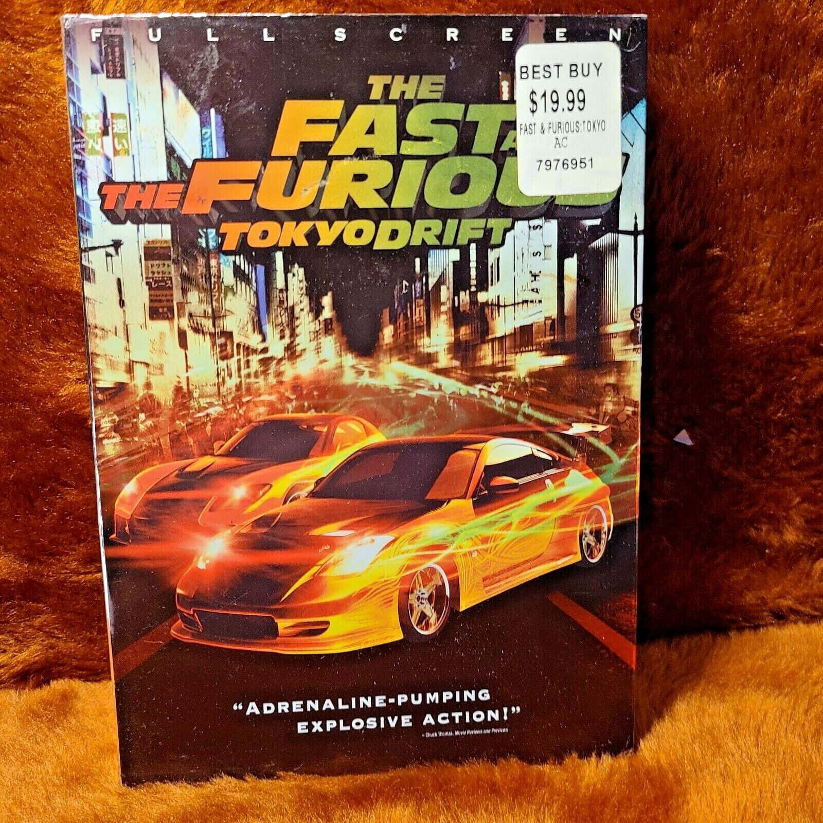 Fast And Furious 桌布 壁紙 — 《玩命關頭3：東京甩尾》的DVD封面放在毛絨絨的棕色表面上，閃爍著霓虹燈光和飛馳的汽車。