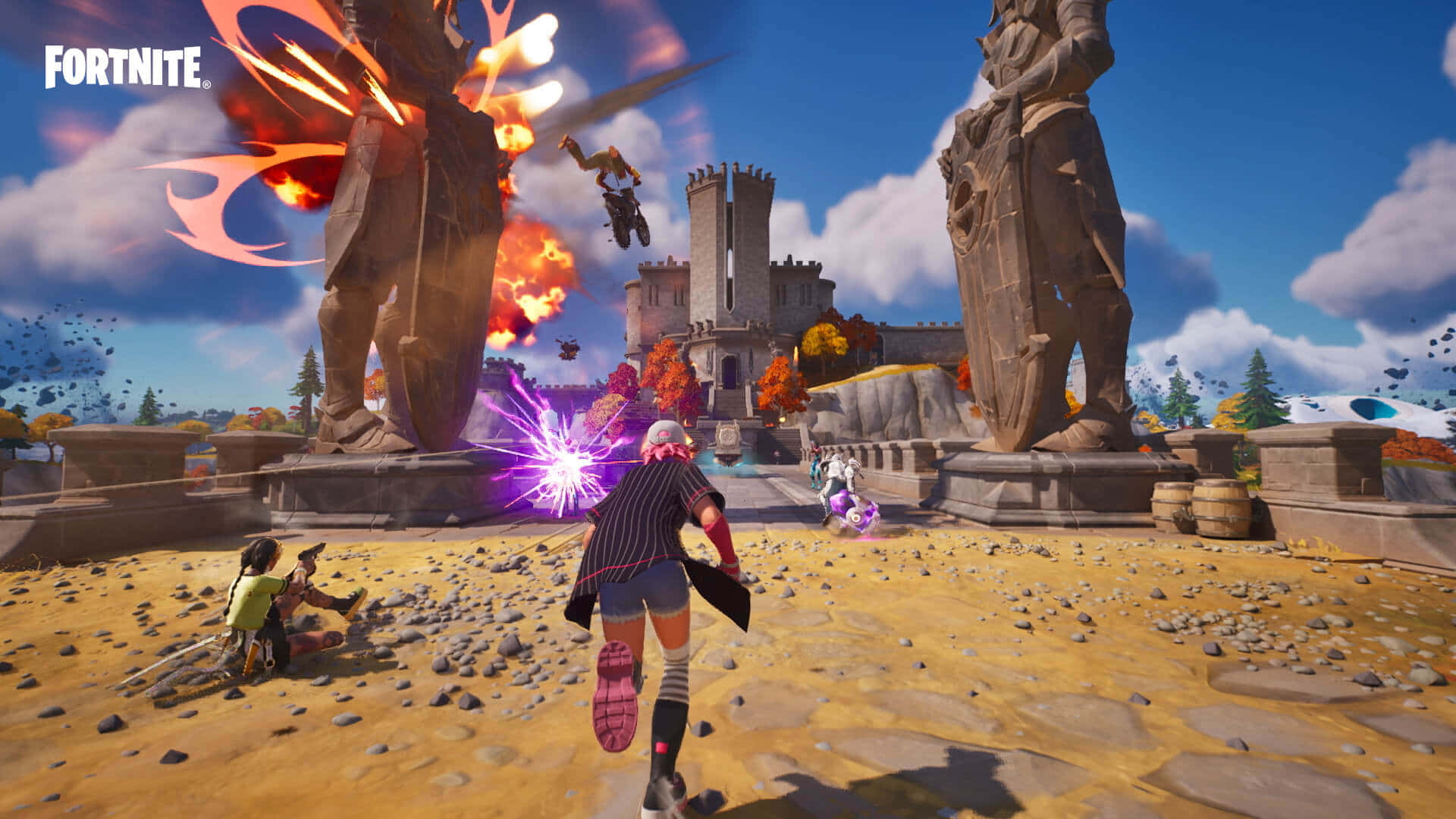 Console Game 桌布 壁紙 — 玩家在明亮的藍天下，於充滿活力的《要塞英雄》競技場中，在巨型雕像和爆炸之間戰鬥。