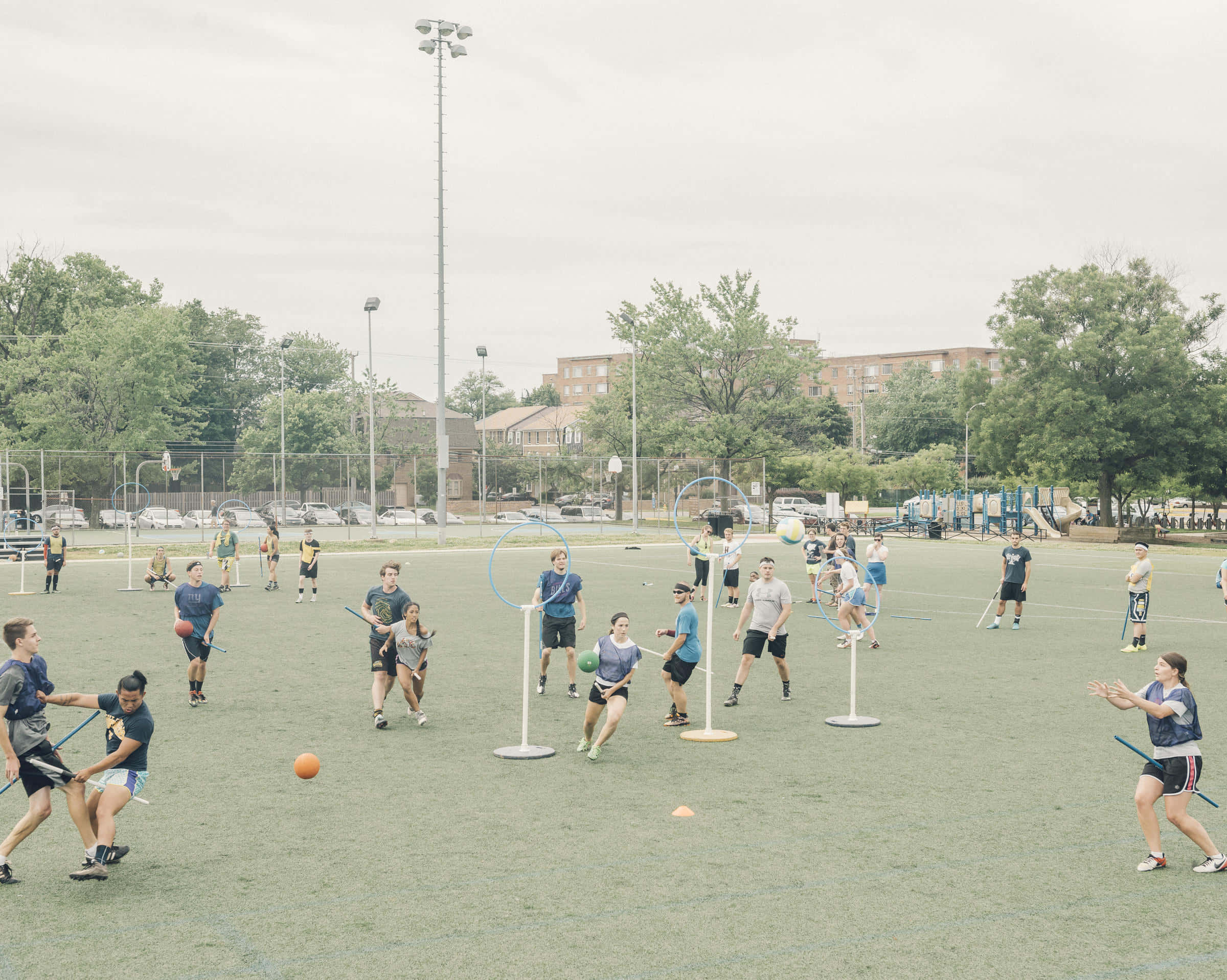 Quidditch 桌布 壁紙 — 玩家在陰天的綠色球場上進行一場熱鬧的戶外閃避球比賽。