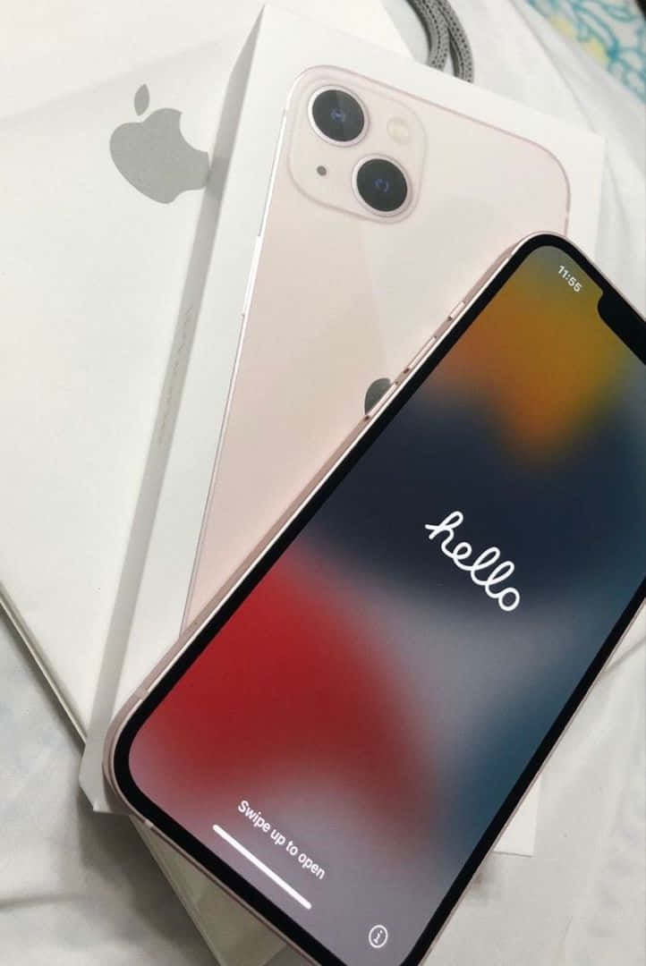 iPhone 12 桌布 壁紙 — 玫瑰金 iPhone 11 放在白色盒子上，置於床單上，螢幕顯示 'hello'，背景為彩色漸變。