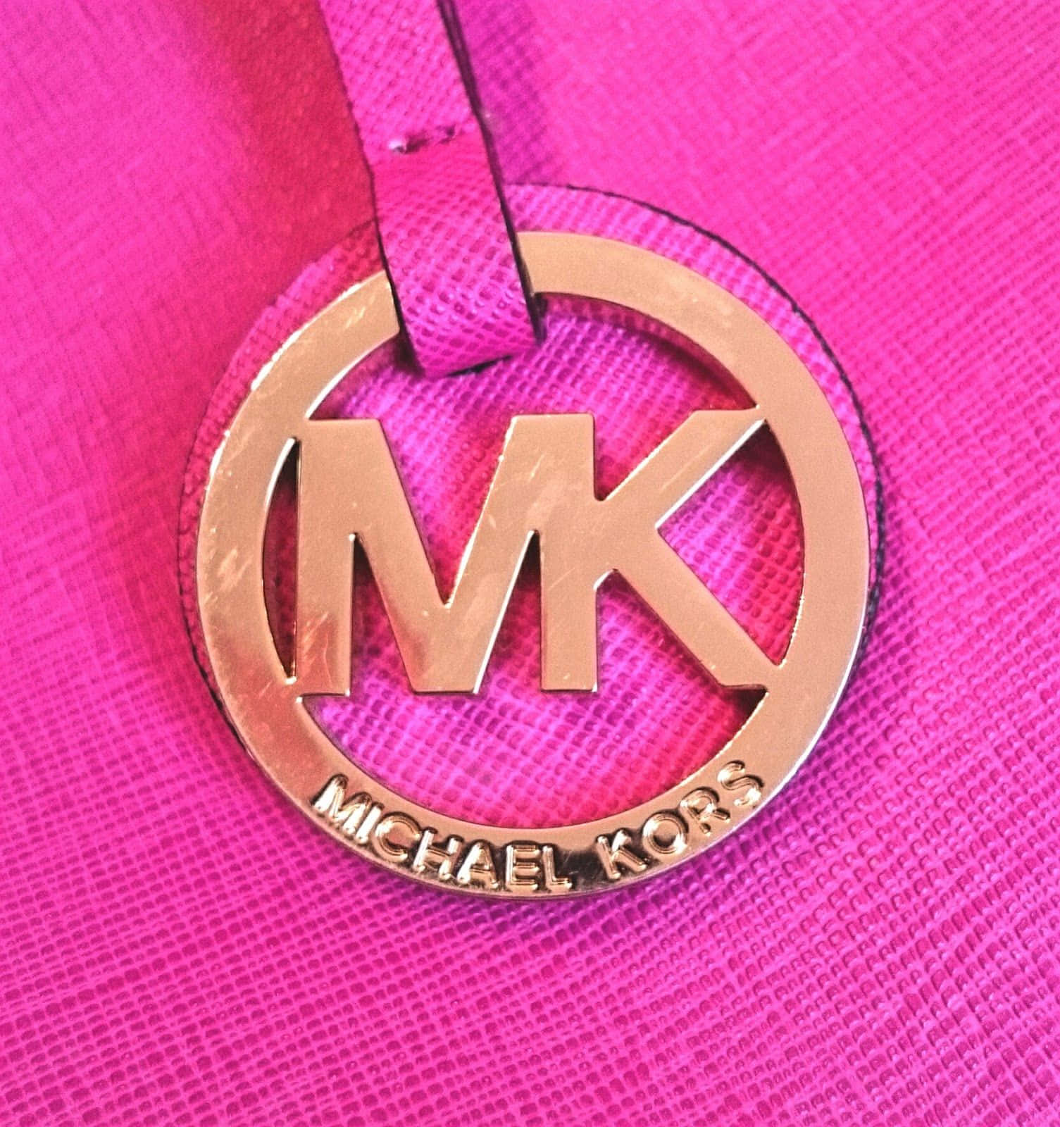 麥可·寇斯 桌布 壁紙 — 玫瑰金色Michael Kors標誌吊飾在充滿活力的粉紅色紋理皮革上的特寫。