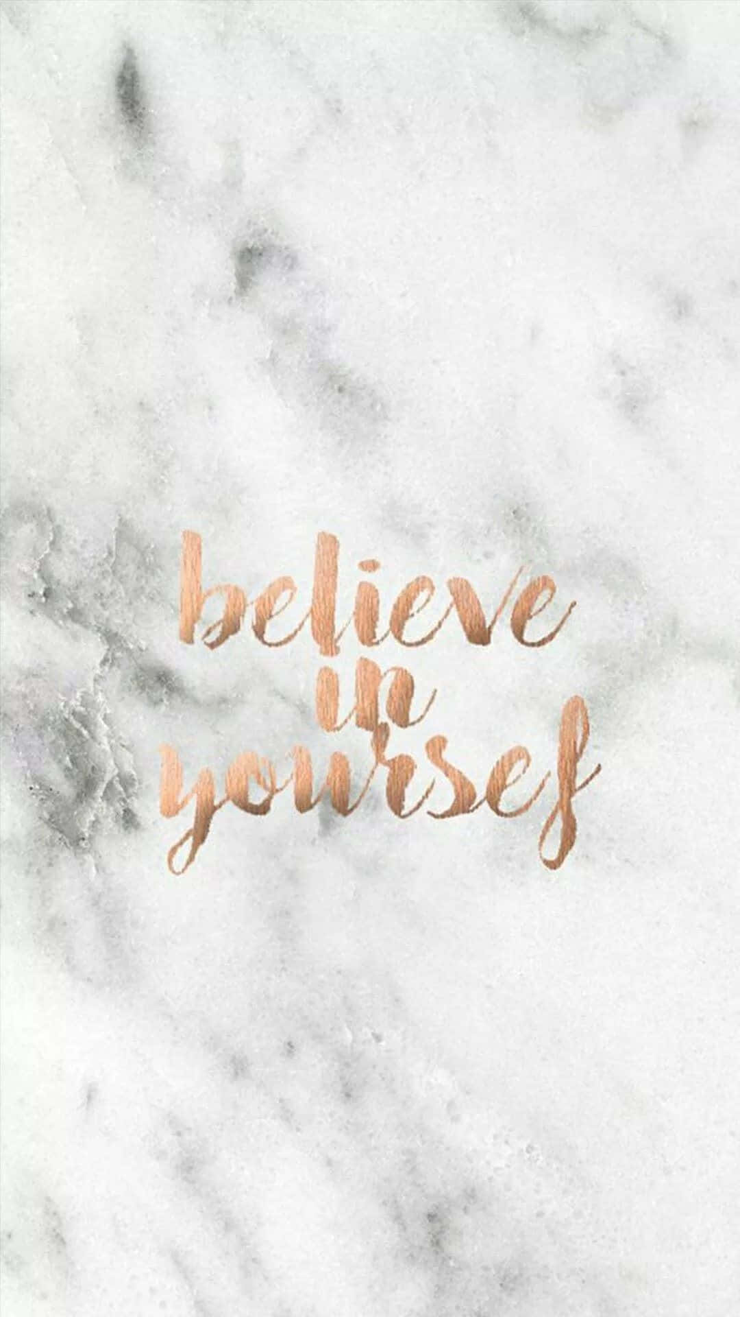 Marble Phone 桌布 壁紙 — 玫瑰金色草書文字寫著「believe in yourself」，疊加在帶有灰色紋理的白色大理石背景上。
