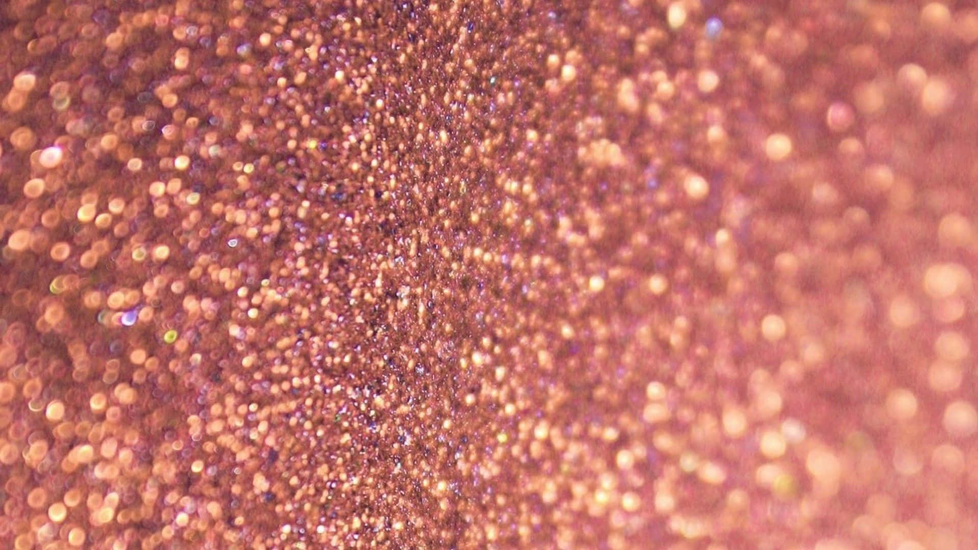 Glitter Rose Gold 桌布 壁紙 — 玫瑰金色閃粉顆粒的特寫，帶有柔和散景高光，營造出閃閃發光的紋理表面。