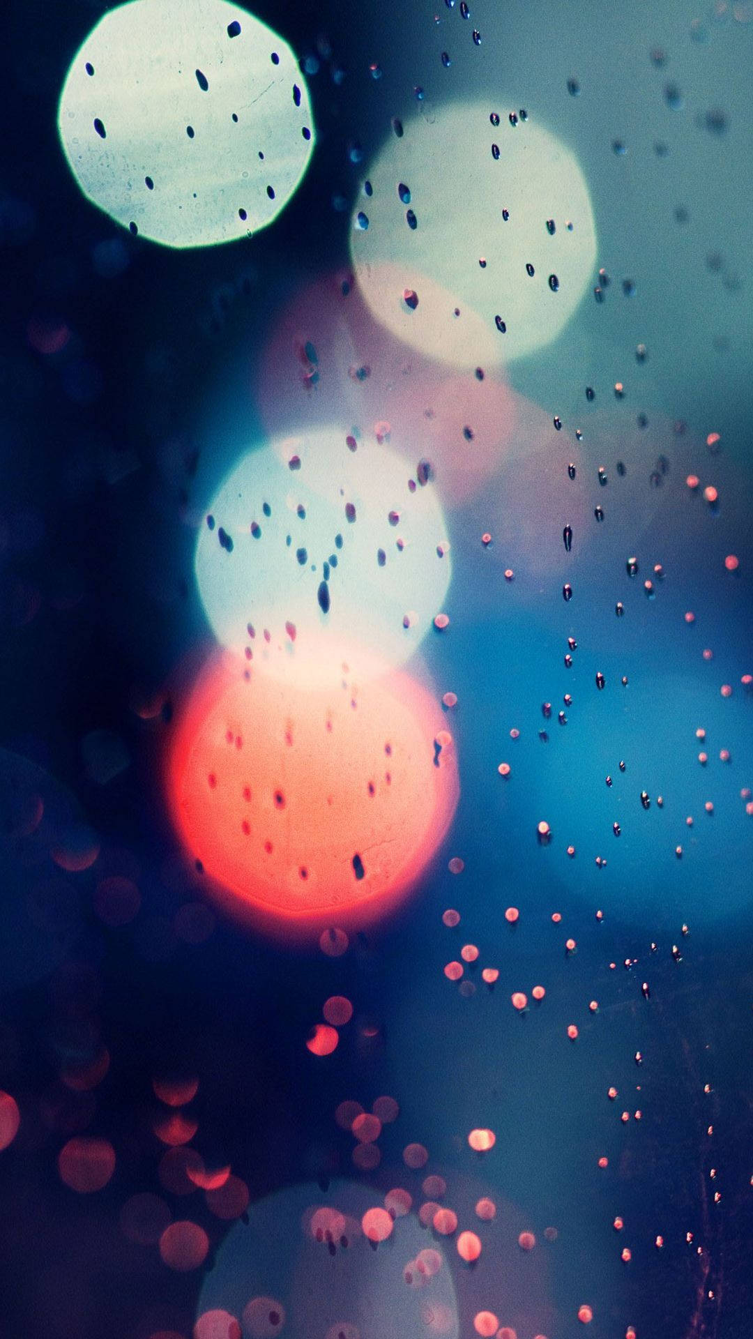 美學 桌布 壁紙 — 玻璃上的雨滴將城市燈光模糊成柔和發光的紅色、藍色和白色圓圈。