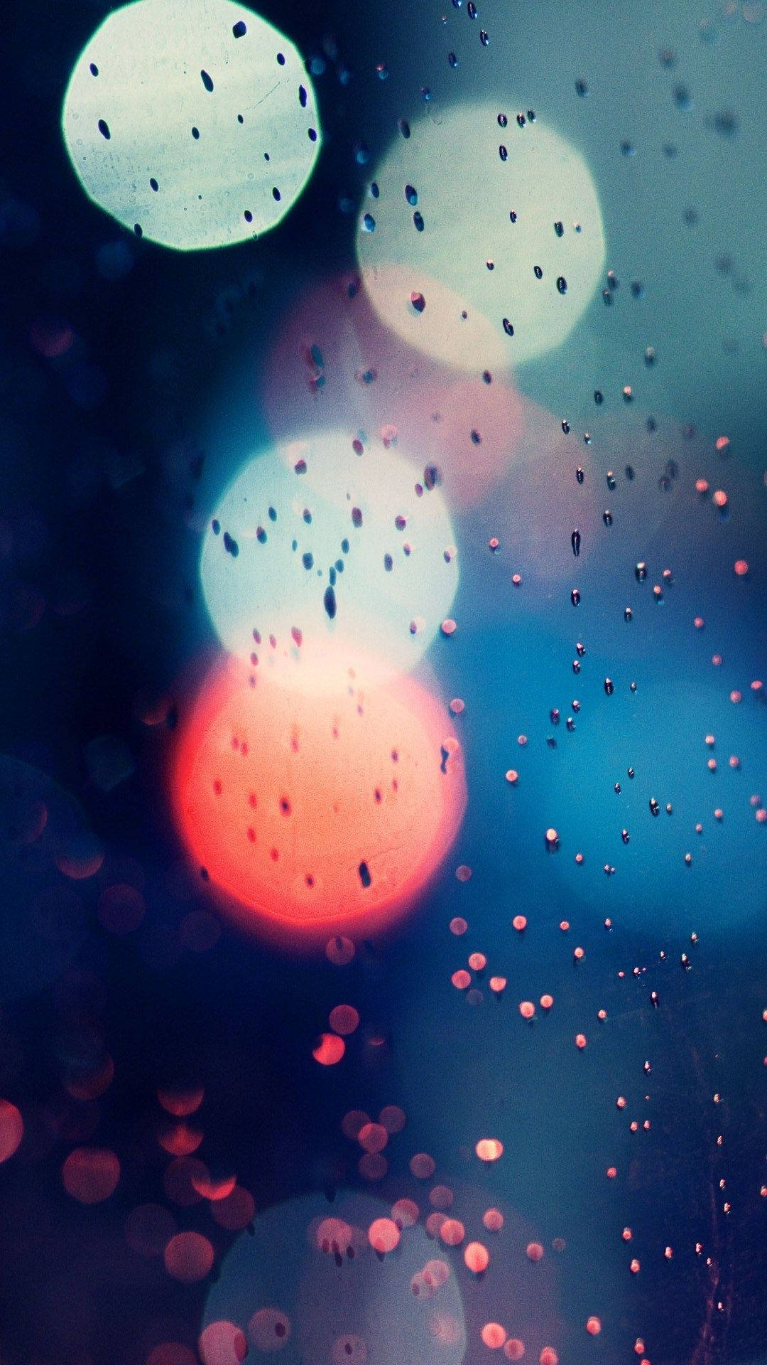 Amazing 桌布 壁紙 — 玻璃上的雨滴將城市燈光模糊成柔和發光的紅色和藍色球體。