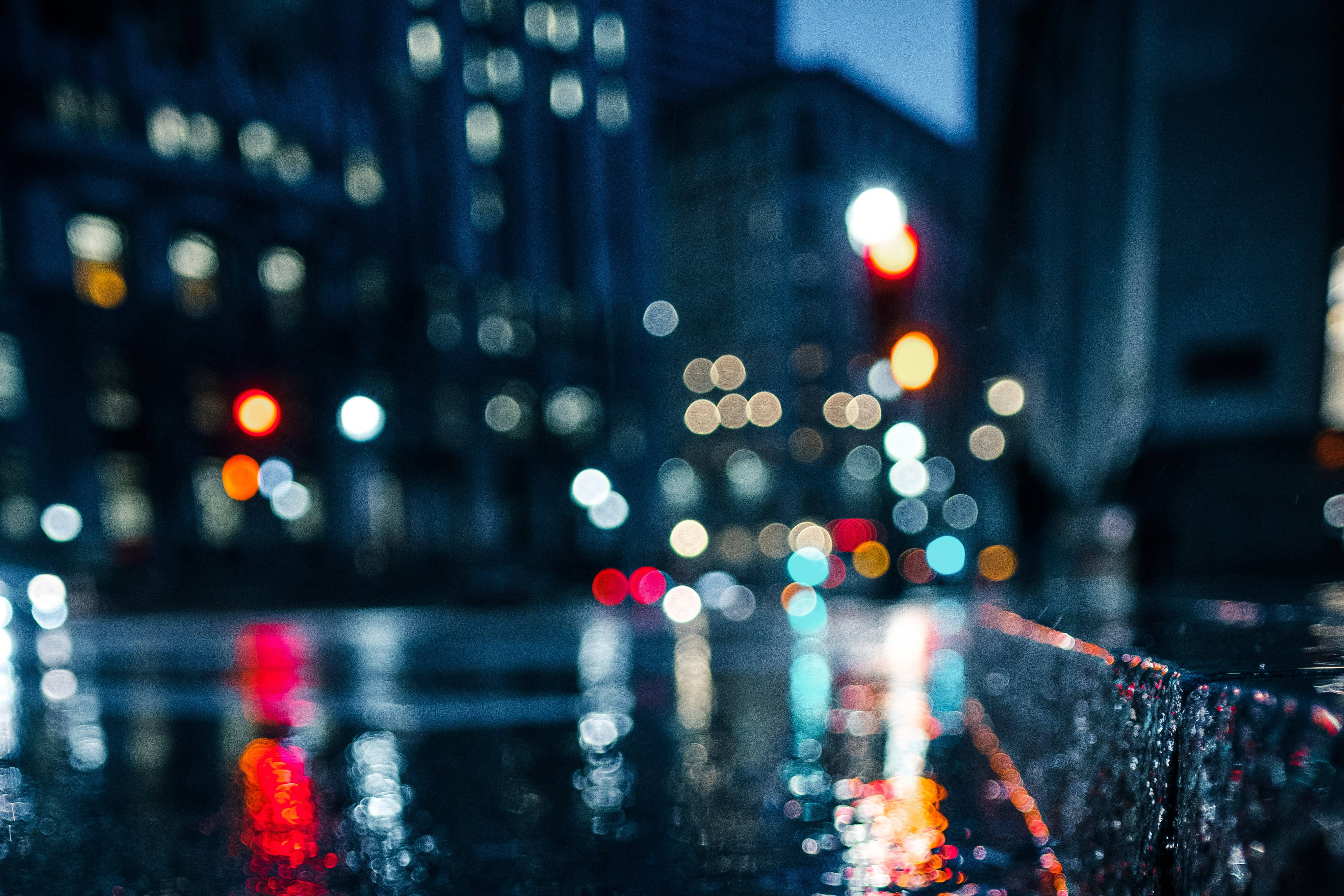 X 桌布 壁紙 — 玻璃上的雨滴將城市燈光模糊成發光球體，在夜間濕漉漉的人行道上反射。