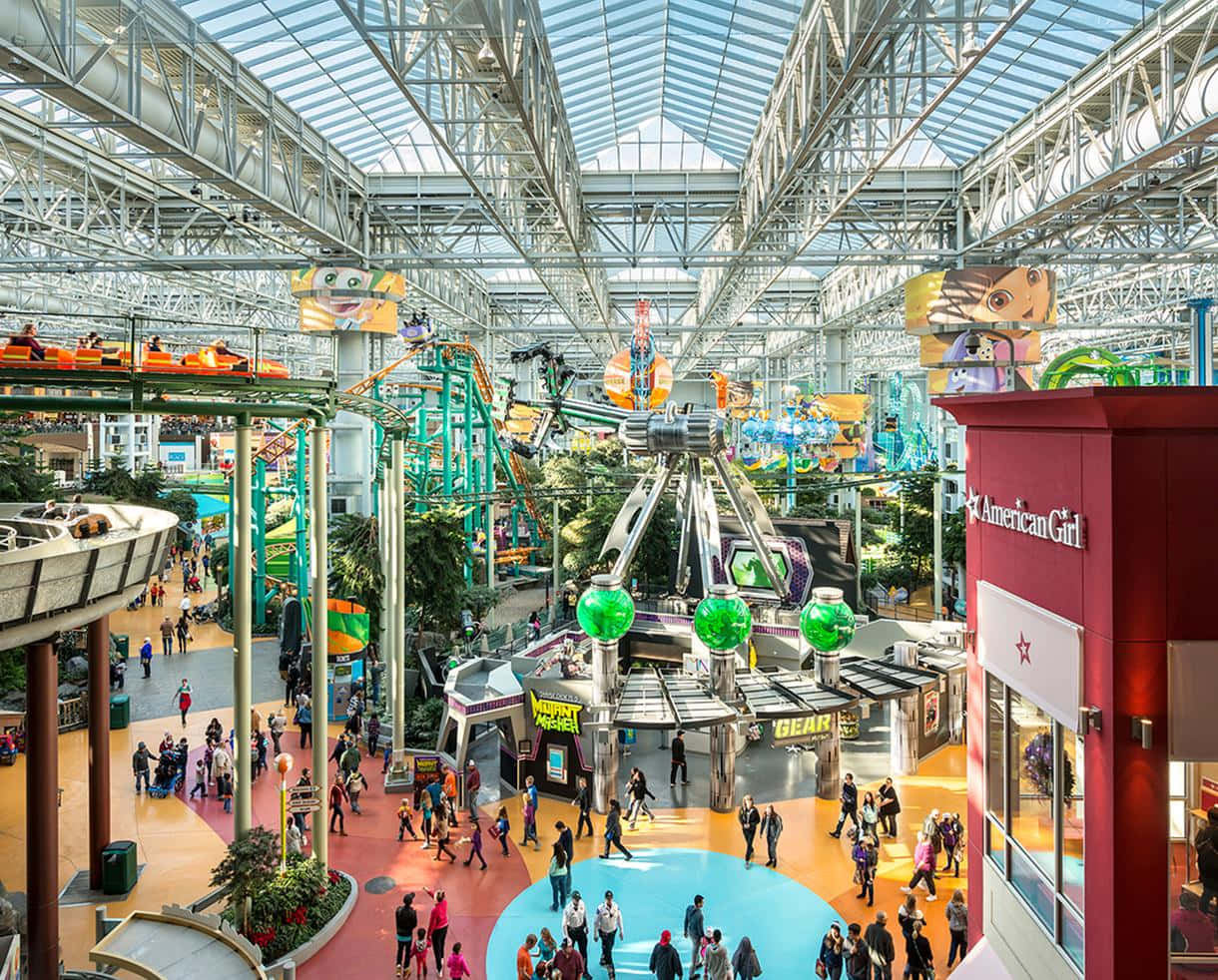 Mall Of America 桌布 壁紙 — 玻璃屋頂下一個熙熙攘攘的室內遊樂園，充滿色彩繽紛的遊樂設施和人群。