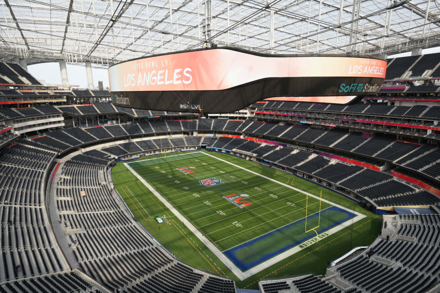 Sofi Stadium 桌布 壁紙 — 玻璃屋頂下空無一人的NFL體育場，擁有綠色草坪和黑色座椅的鳥瞰圖。