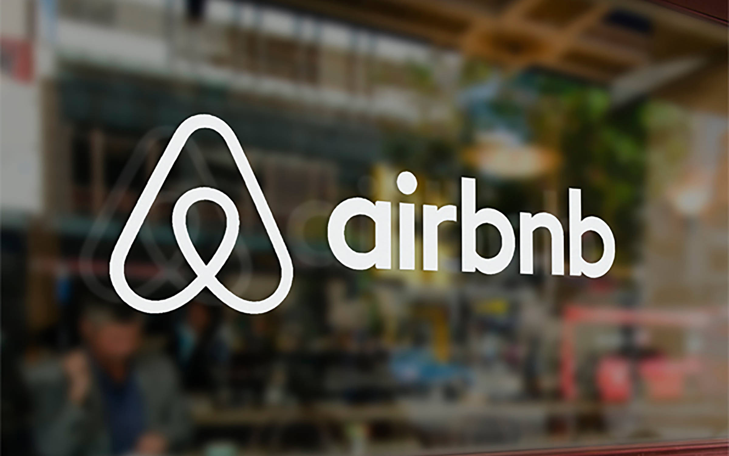 標誌 桌布 壁紙 — 玻璃店面上白色Airbnb標誌貼紙，模糊的室內背景。