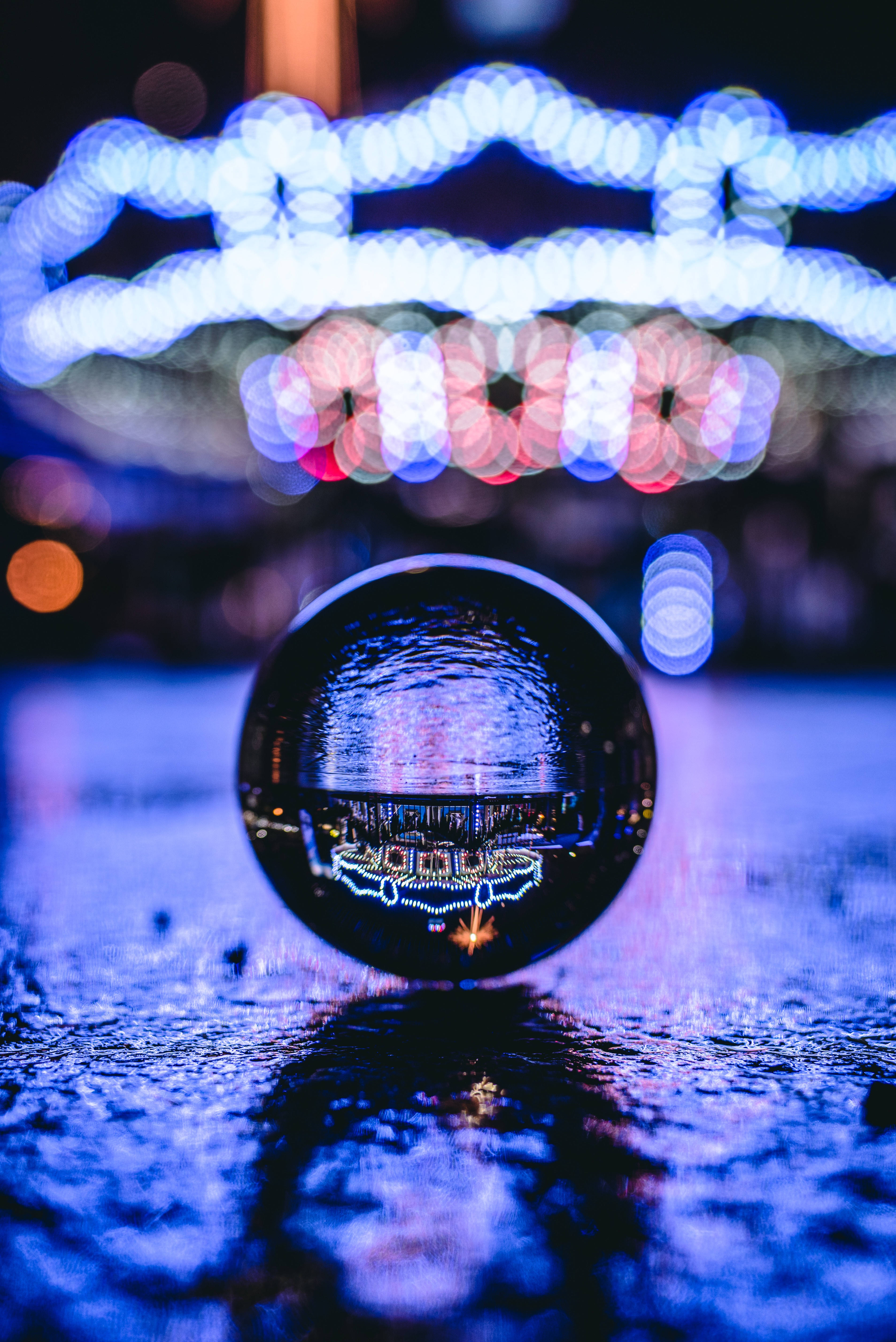 Transparent 桌布 壁紙 — 玻璃球在散景夜空下，在濕漉漉的路面上反射出充滿活力的城市燈光。