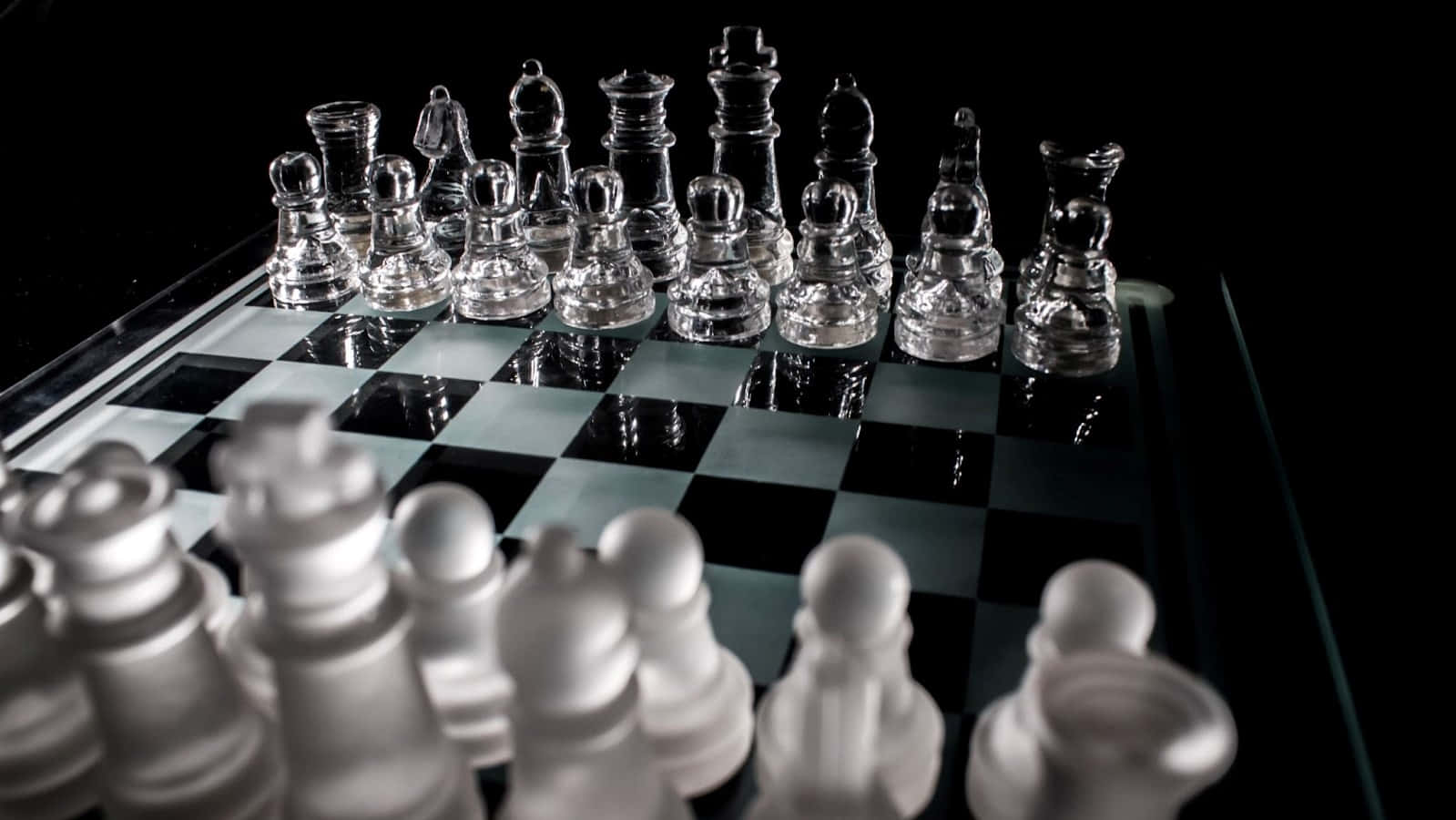 Chessboard 桌布 壁紙 — 玻璃西洋棋棋子放在反光棋盤上，淺景深，黑色背景。