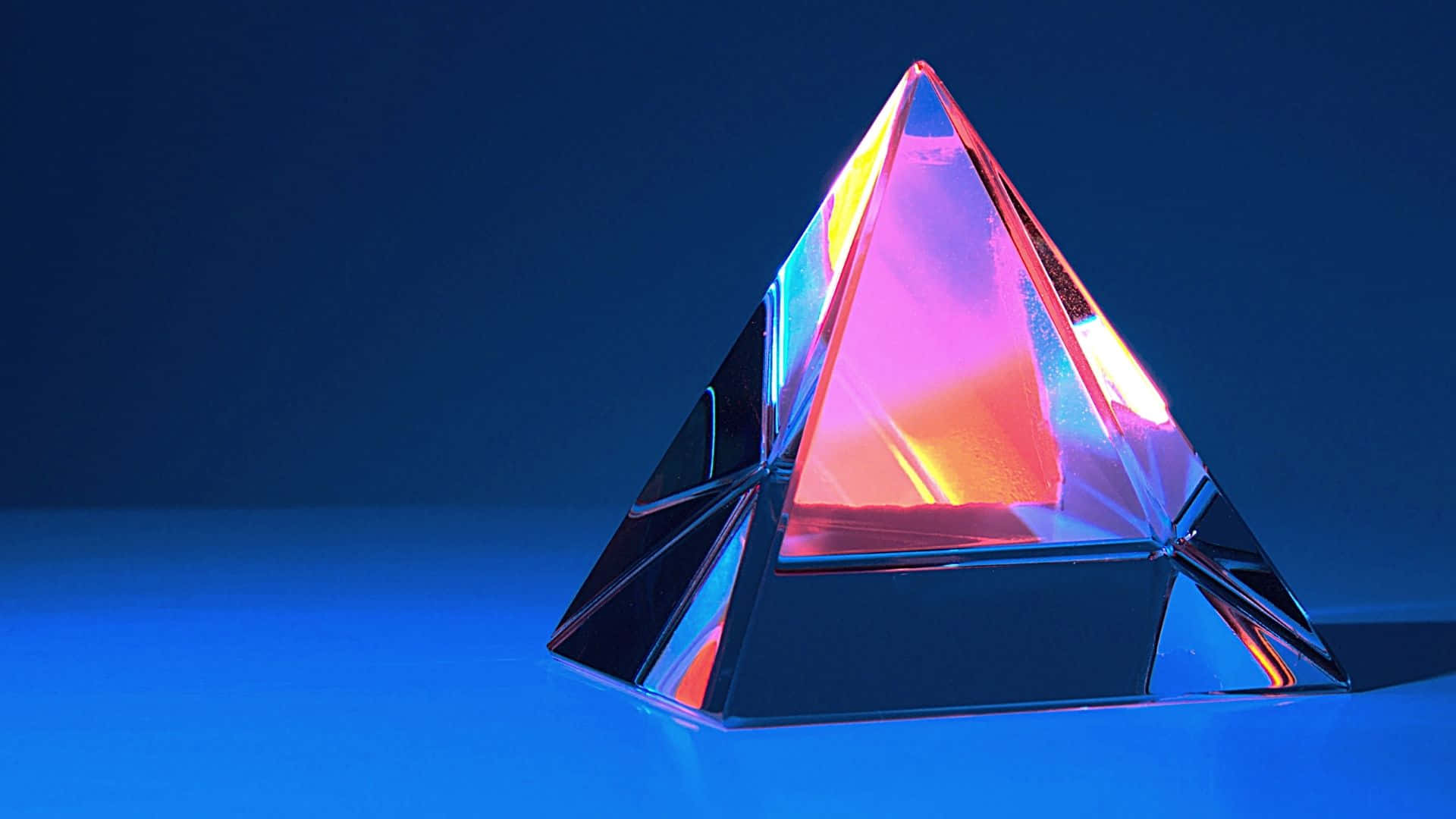 水晶 桌布 壁紙 — 玻璃金字塔在深藍色工作室背景上折射出鮮豔的霓虹燈光。