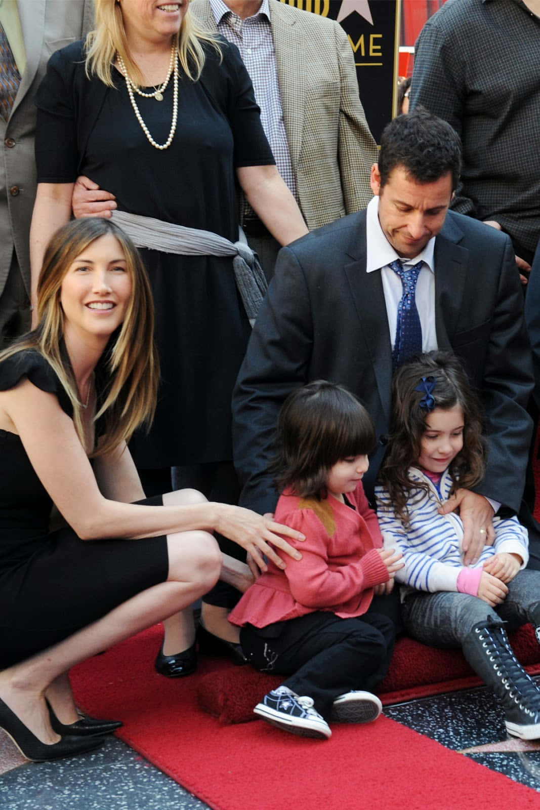 Adam Sandler 桌布 壁紙 — 珍妮佛·安妮斯頓與她的家人在好萊塢星光大道典禮上於紅地毯上擺姿勢，展現笑容和有趣的互動。