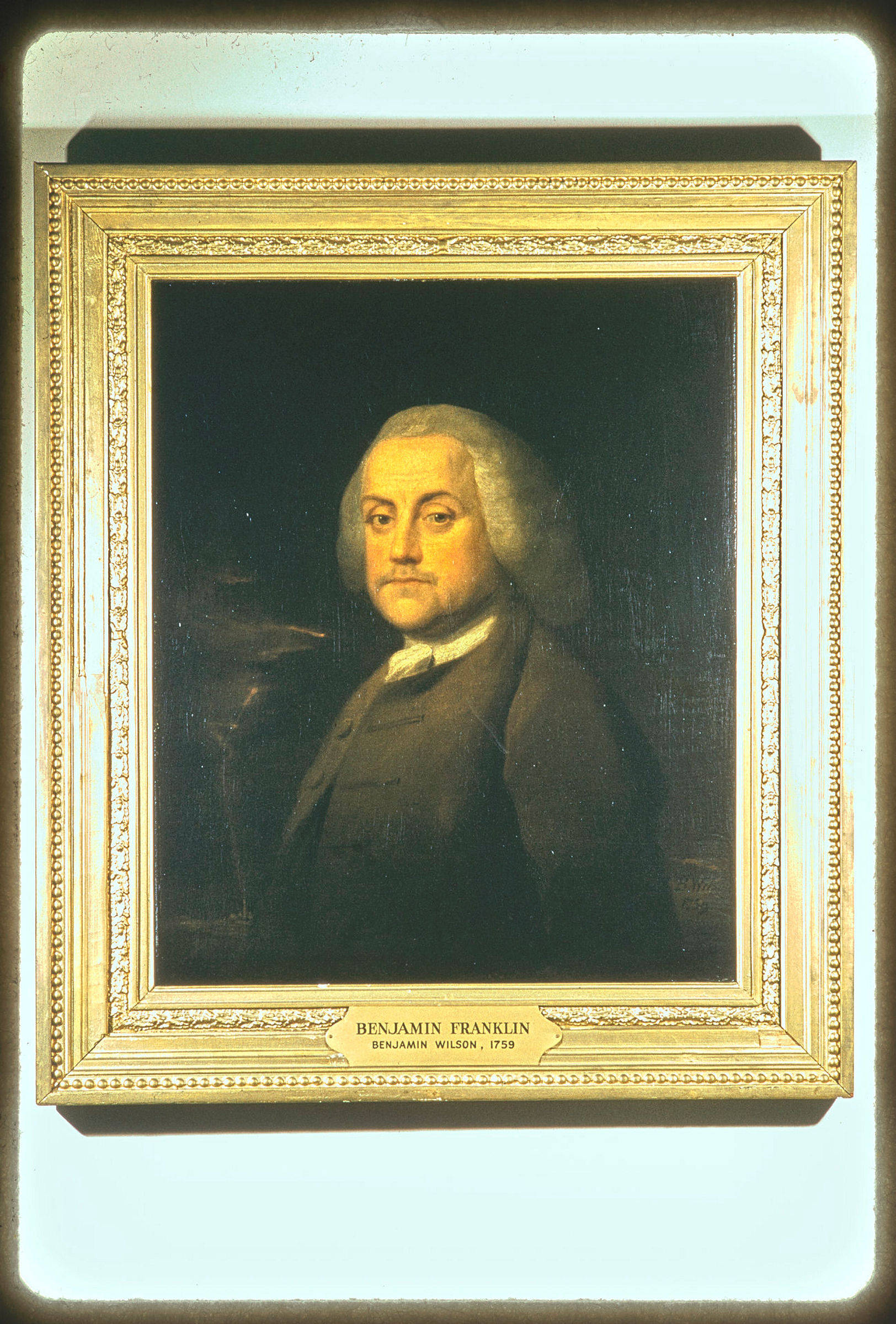 Franklin 桌布 壁紙 — 班傑明·富蘭克林的古典油畫肖像，身穿深色外套和撲粉假髮，鑲嵌在華麗金色畫框中，掛在淺色牆上。
