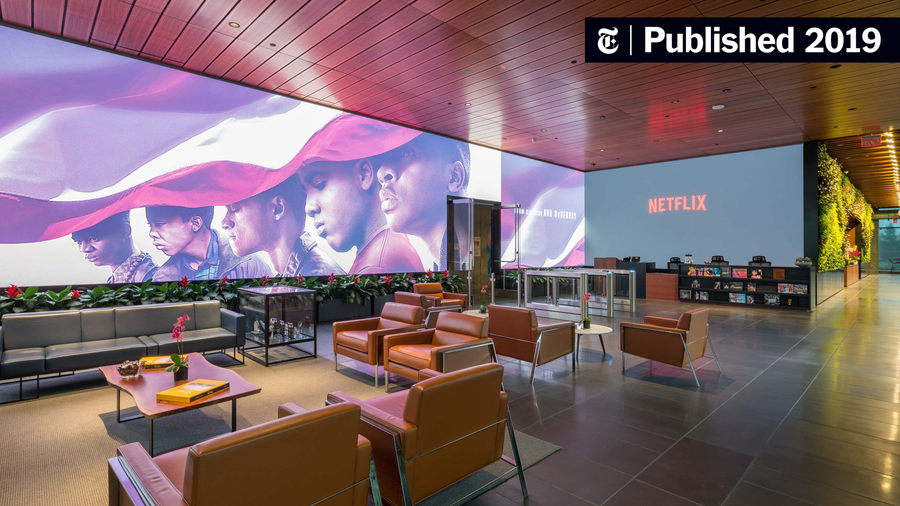 Netflix 桌布 壁紙 — 現代Netflix大廳，設有橙色椅子，溫暖木天花板下有一幅巨大壁畫，描繪多元面孔。