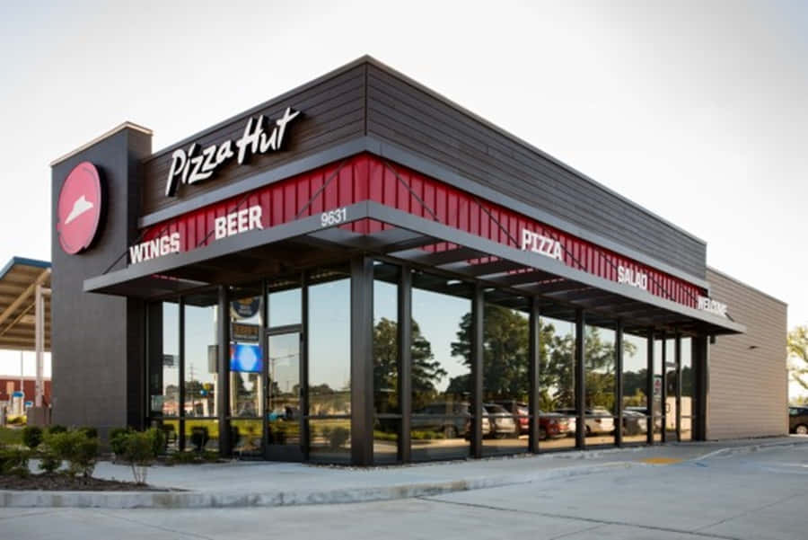 日落時分，Pizza Hut餐廳外觀紅黑相間，配有玻璃窗。