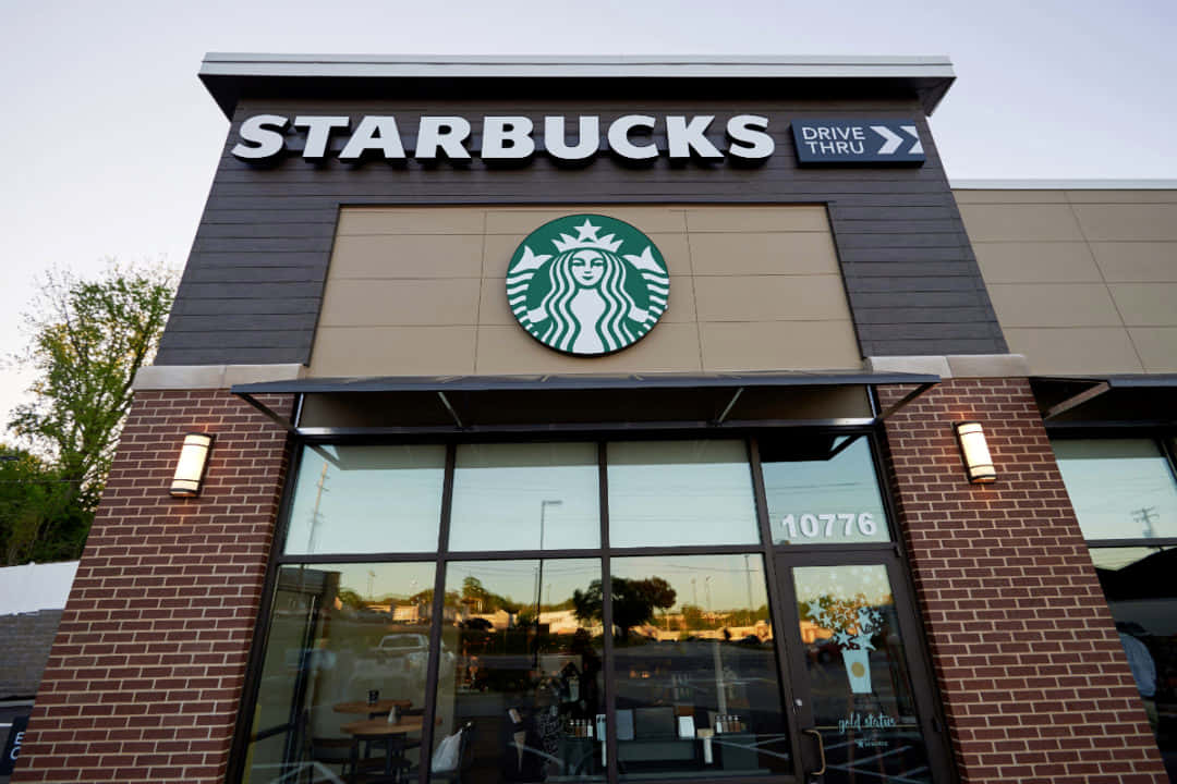 星巴克 桌布 壁紙 — 現代Starbucks店面，磚砌外牆和大玻璃窗，映照出暮色中的郊區街道。