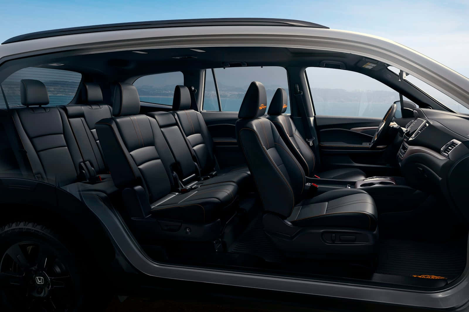Honda Pilot 桌布 壁紙 — 現代SUV的豪華黑色皮革內裝，在晴朗藍天下可欣賞海洋和遠處山丘的全景。