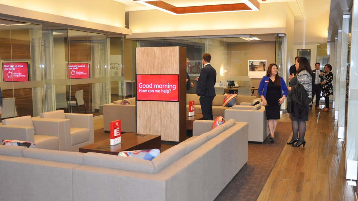 Bank Of America 桌布 壁紙 — 現代企業大廳，設有米色沙發、木地板，員工在溫暖的頭頂燈光下迎接訪客。