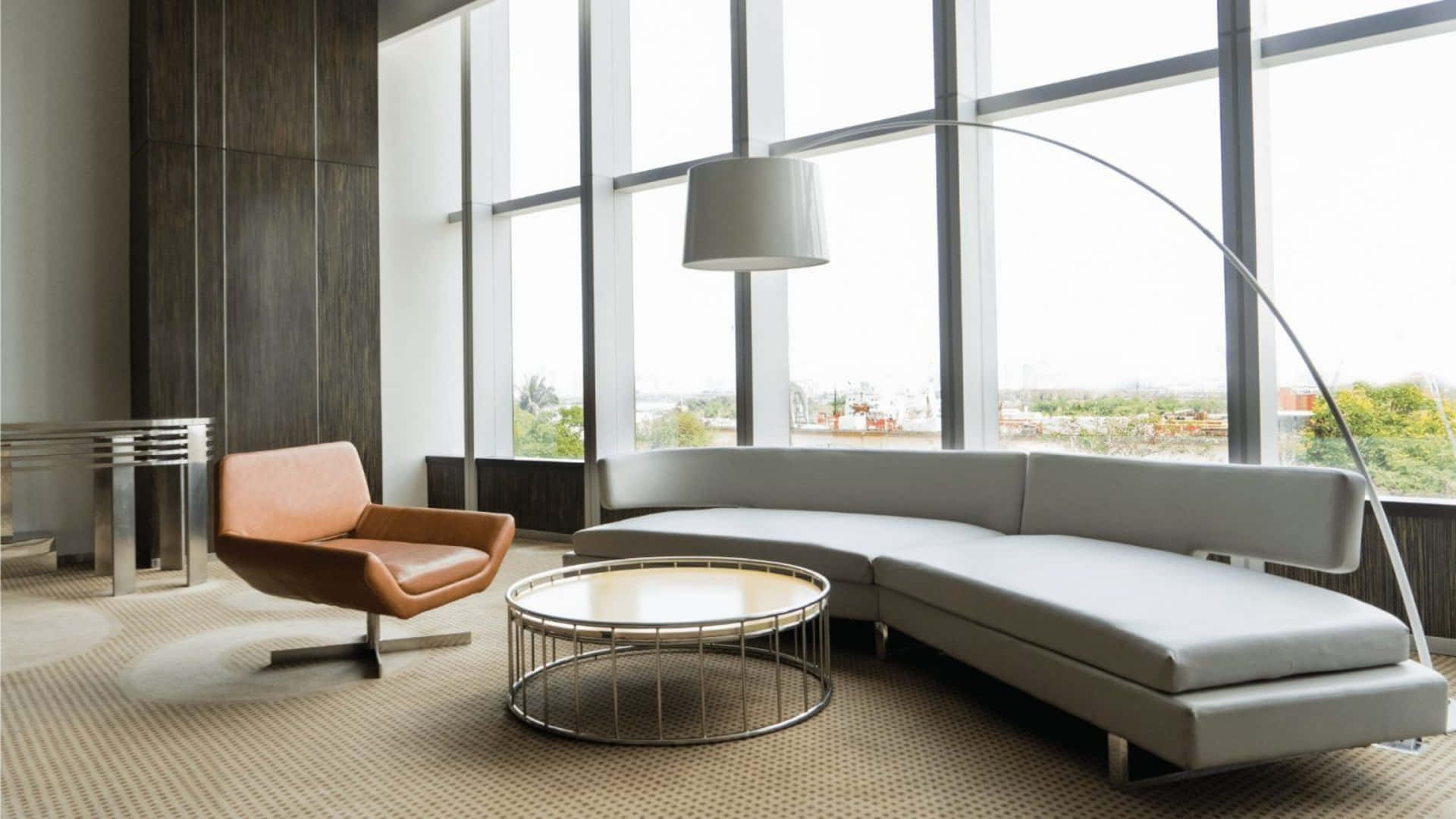 Interior Design 桌布 壁紙 — 現代休息室，配有灰色組合沙發、棕色皮革椅子和弧形落地燈，沐浴在大窗戶的自然光中。