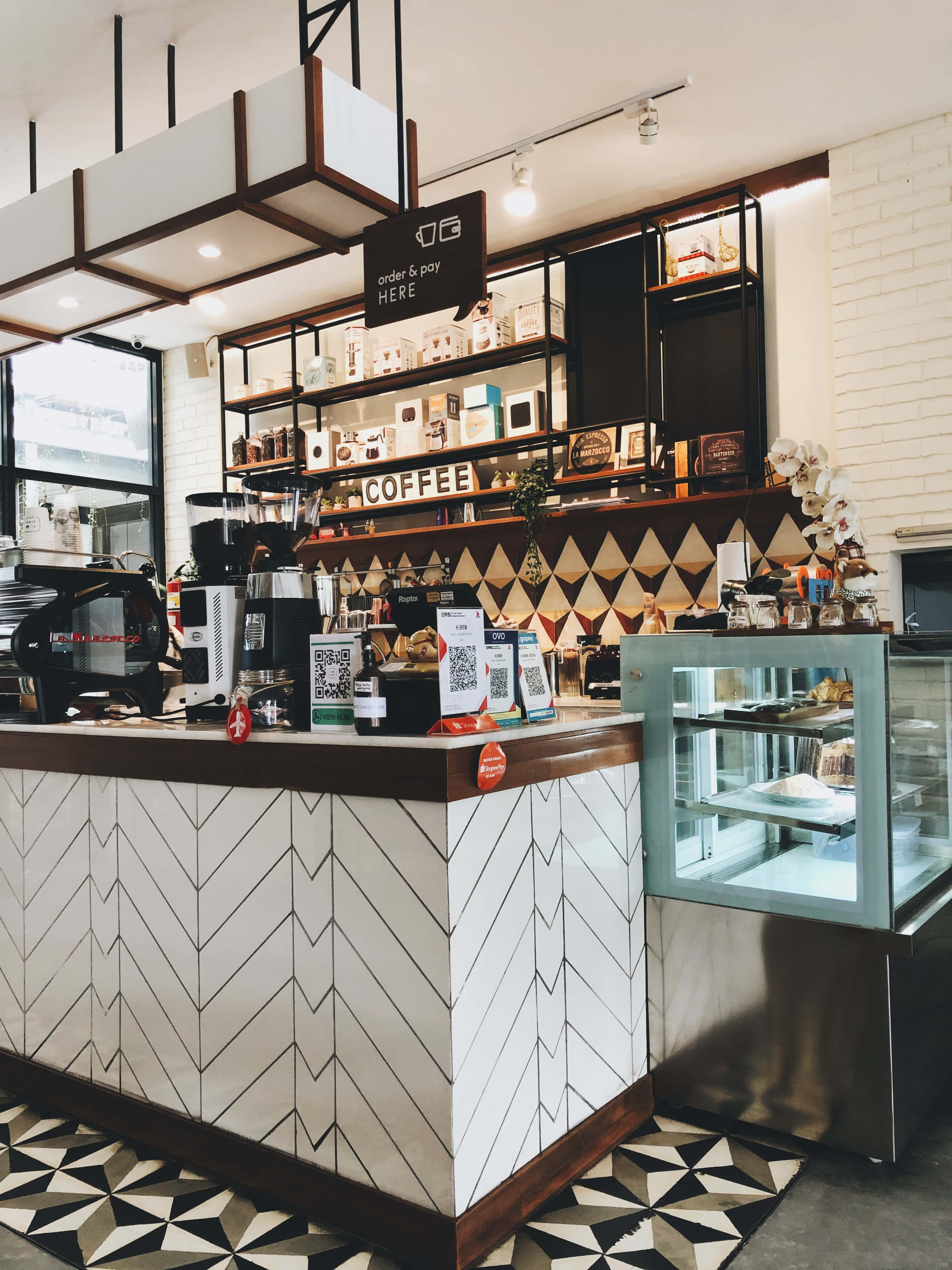 Restaurant 桌布 壁紙 — 現代咖啡店內部，設有幾何圖案櫃檯和陳列咖啡產品的貨架，光線明亮。
