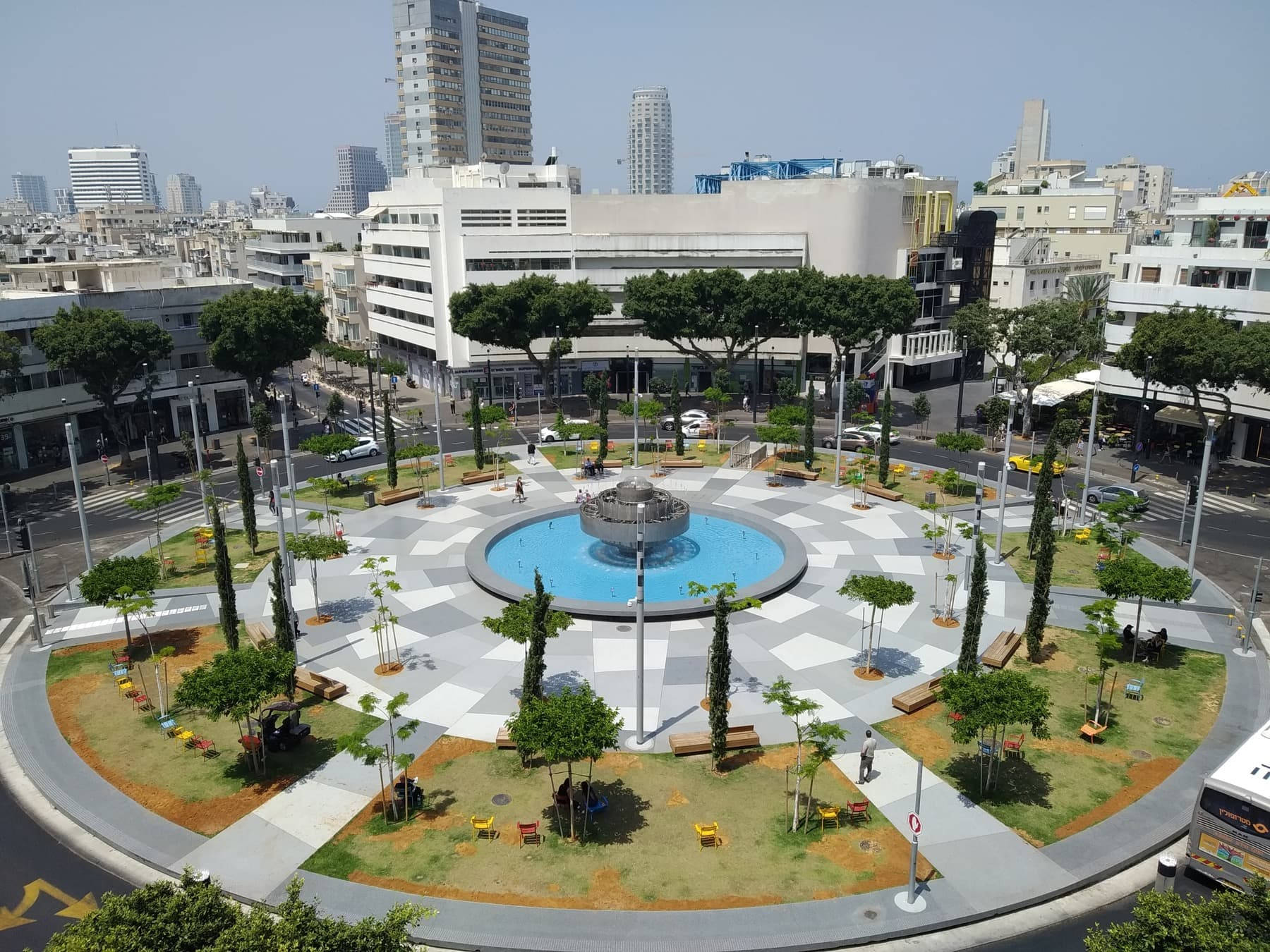 Israel 桌布 壁紙 — 現代城市廣場的鳥瞰圖，中央噴泉周圍環繞著樹木、長椅和幾何圖案鋪裝，在明亮的日光下。